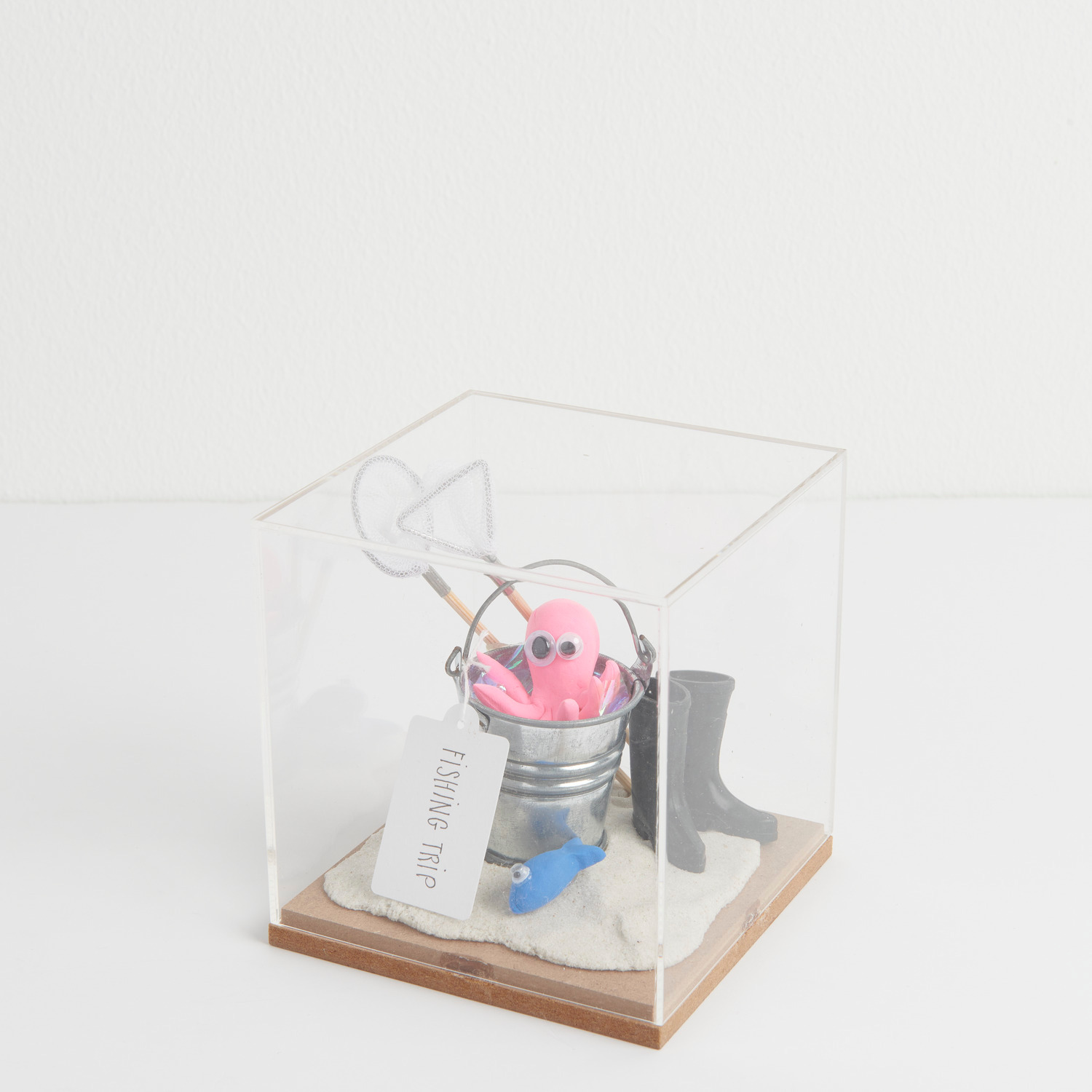 Miniatur Fischkescher: Figurico Dekohaube Würfel mit rosa Oktopus, Eimer und Stiefel auf Sand.