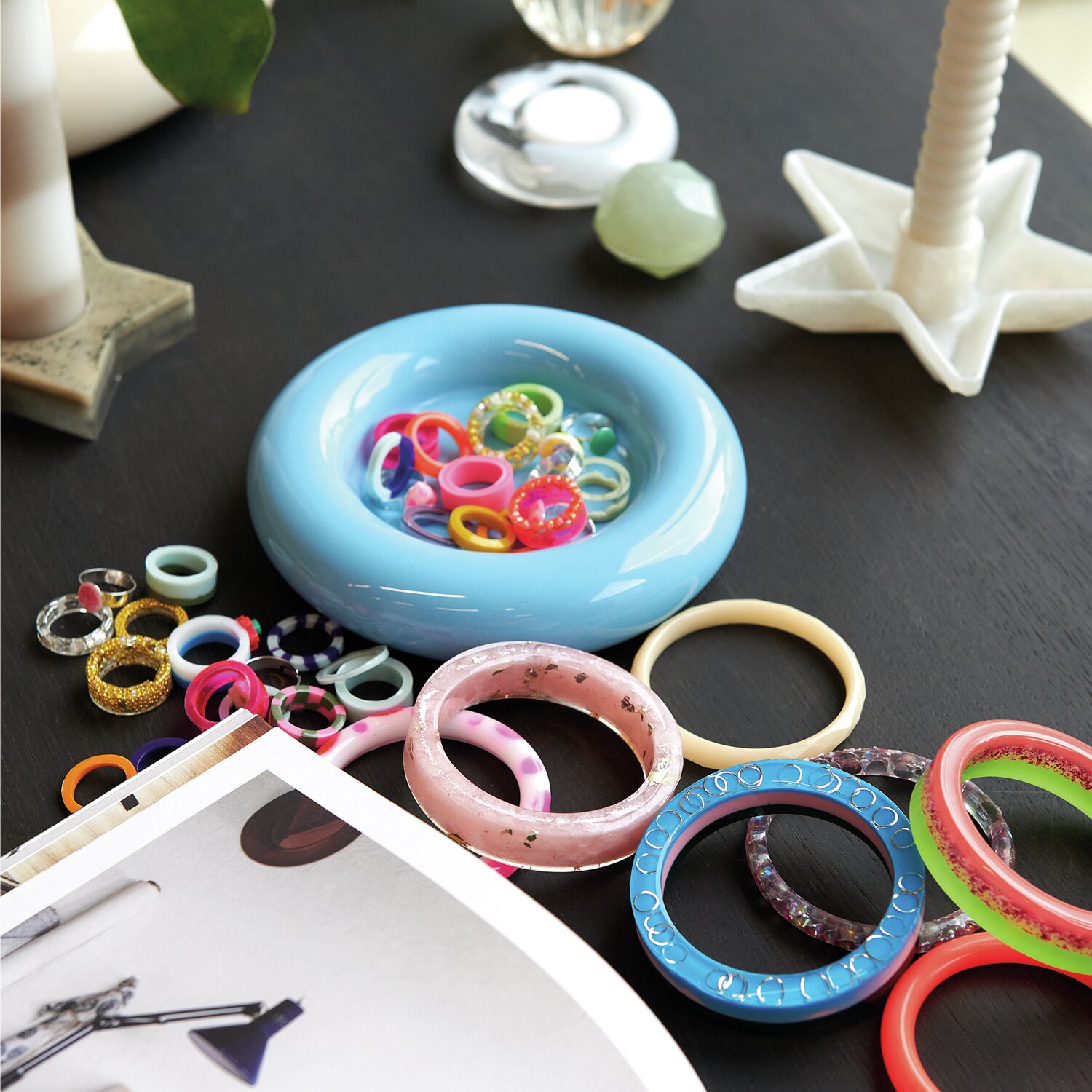 Silikon Gießform Armreif: Verschiedene bunte Ringe in einer blauen Schale auf einem Tisch, ideal für kreative Resin-Projekte.