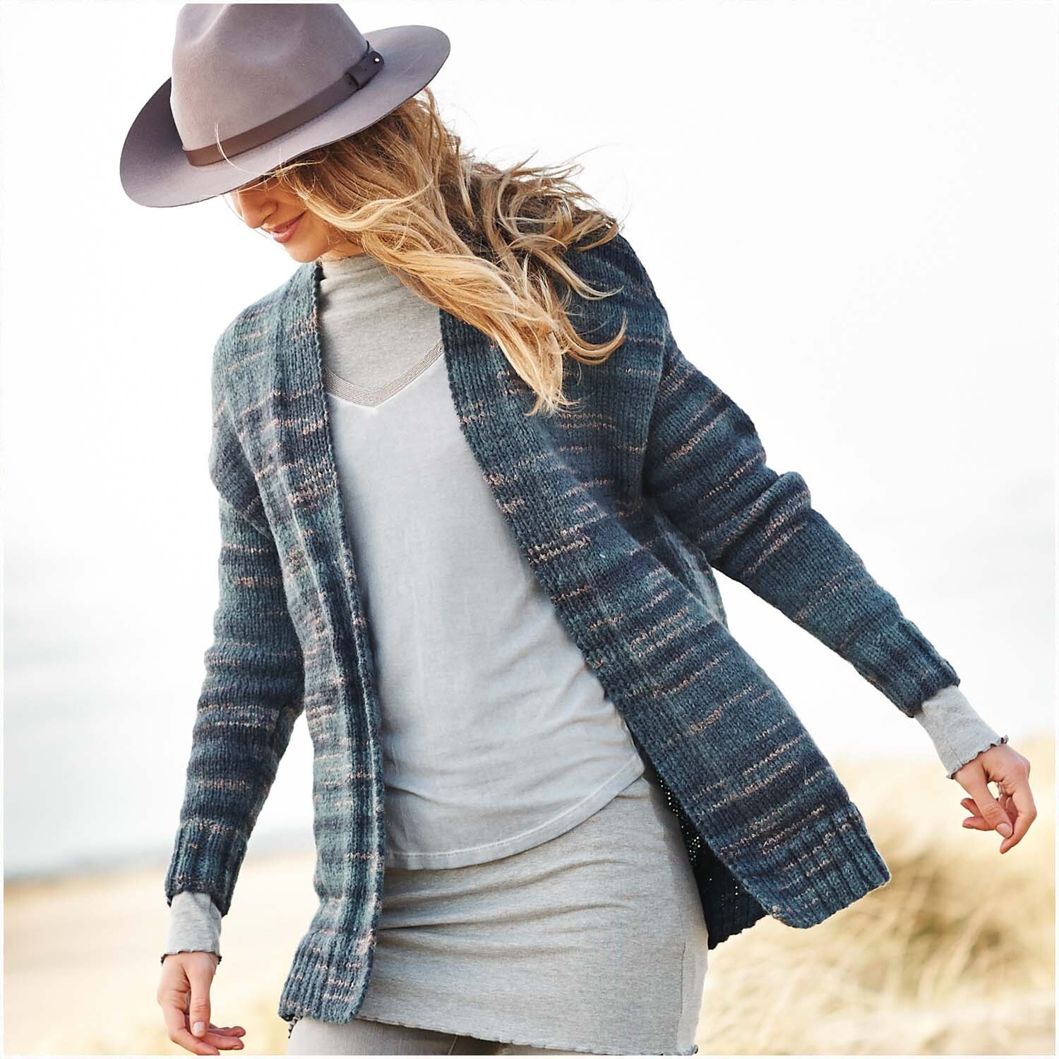 Creative Light Melange Glitz Strickjacke in Blau Mix, getragen von Frau mit grauem Kleid und Hut. Ideal für stilvolle Herbsttage.