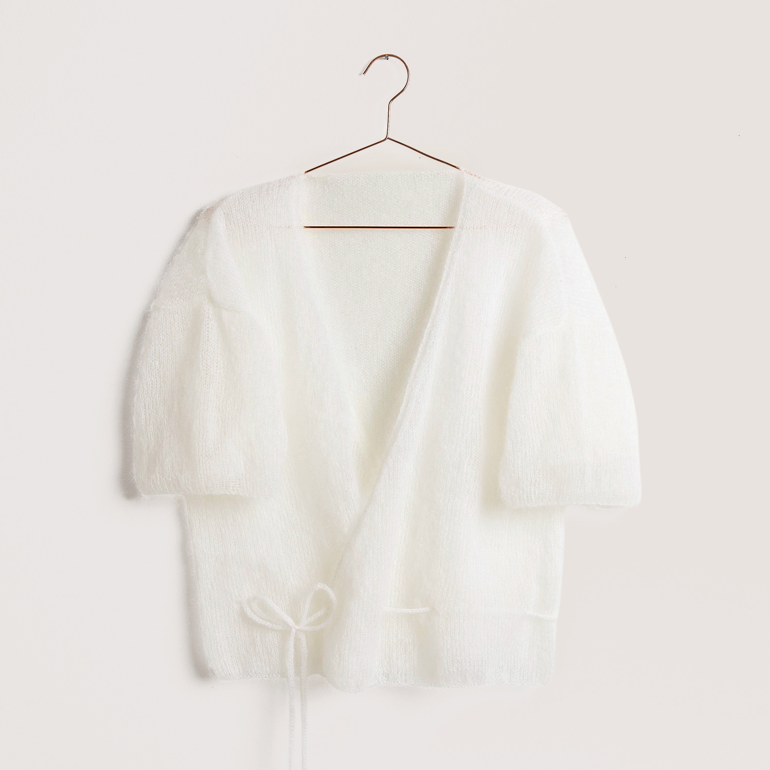 Weißer Pullover auf grauem Hintergrund – zum Strickset