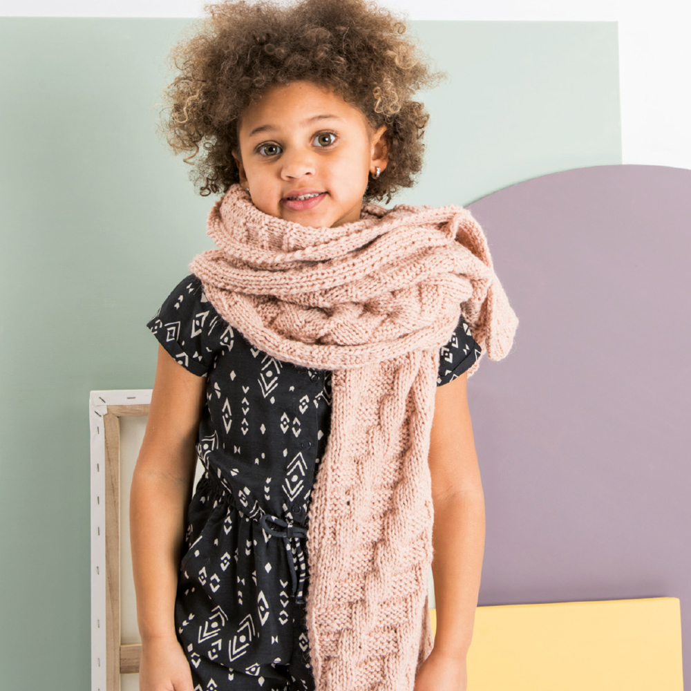 Strickanleitung Schal mit Strukturmuster: Kind trägt einen langen, strukturierten Schal in Beige.