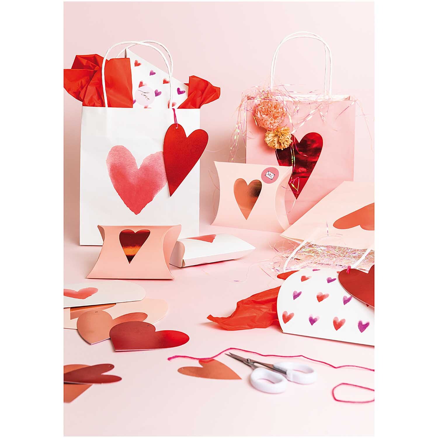 Paper Poetry Papieranhänger zeigen rosa Herzen in einer kreativen Geschenkverpackungsszene. Ideal für romantische Anlässe.