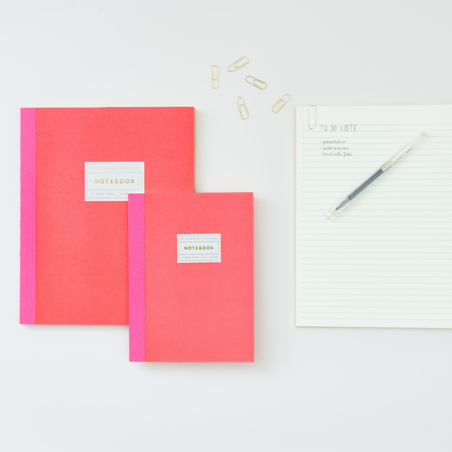 Paper Poetry Notizbuch S und L in Neonrot mit Goldrand von Rico Design neben einer To-Do-Liste und Büroklammern.