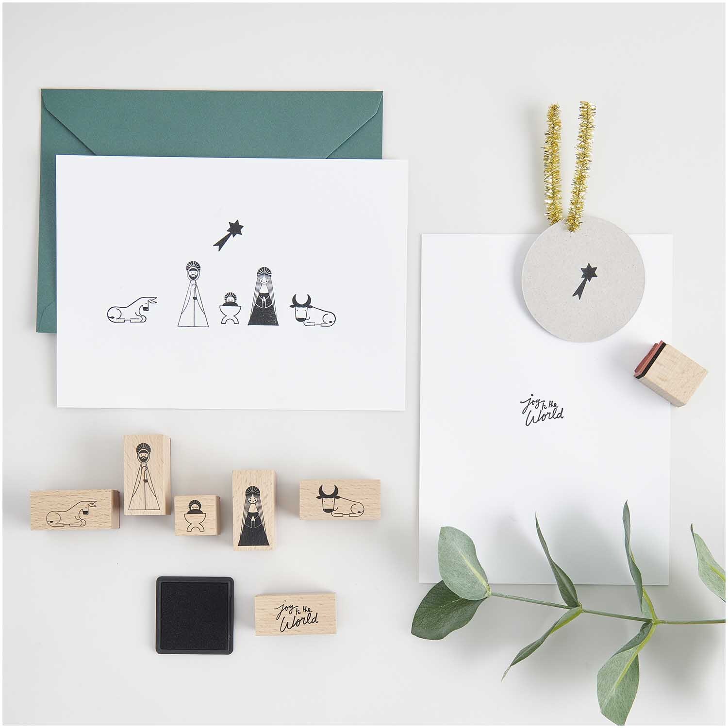 Paper Poetry Stempelset Holy Family, 8-teilig, zeigt Krippenfiguren auf Karten mit Umschlag und Dekoration. Ideal für kreative Weihnachtsprojekte.