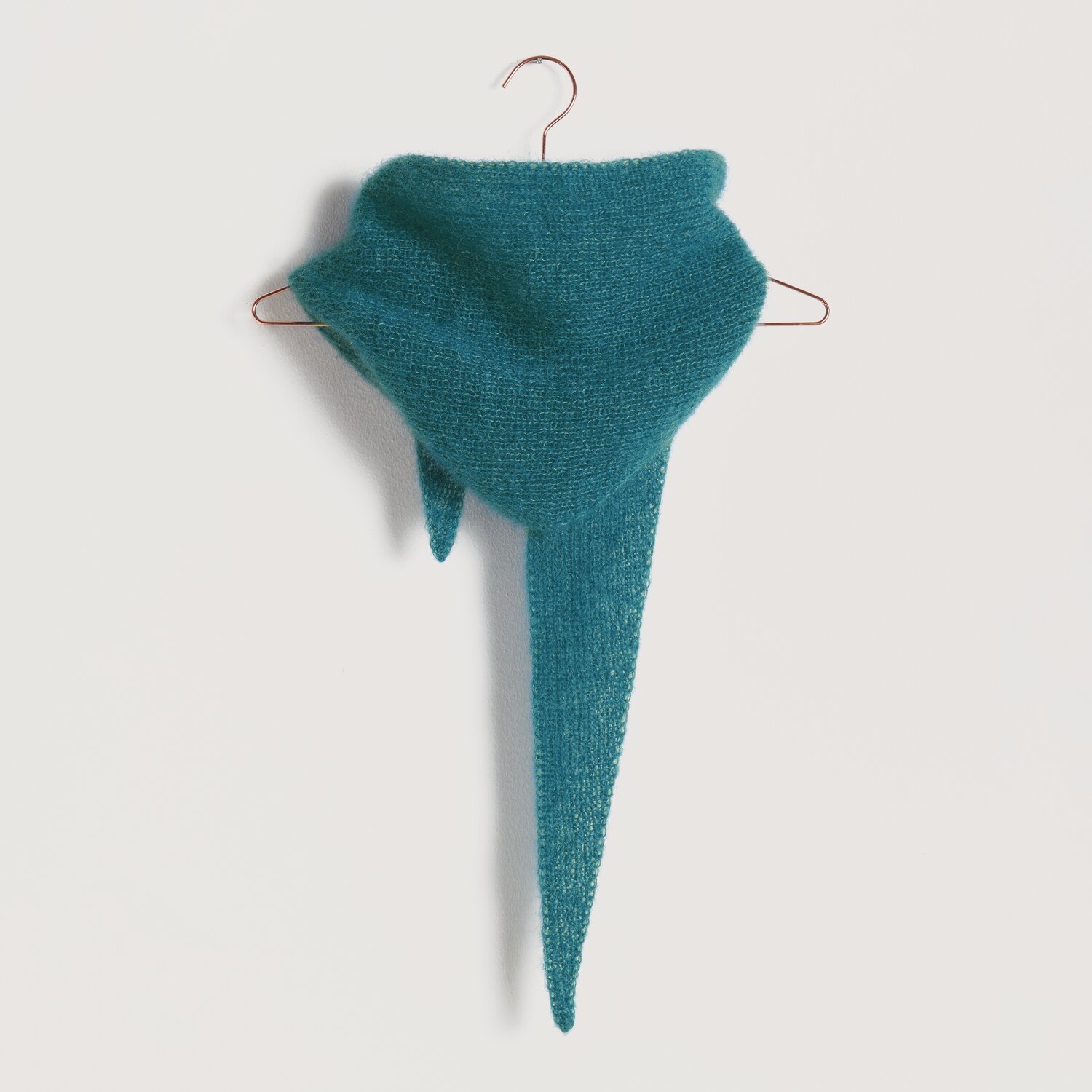 Strickset Dreieckstuch Modell 19: Weiches, türkisfarbenes Tuch auf einem Kleiderbügel. Ideal für stilvolle Handarbeitsprojekte.