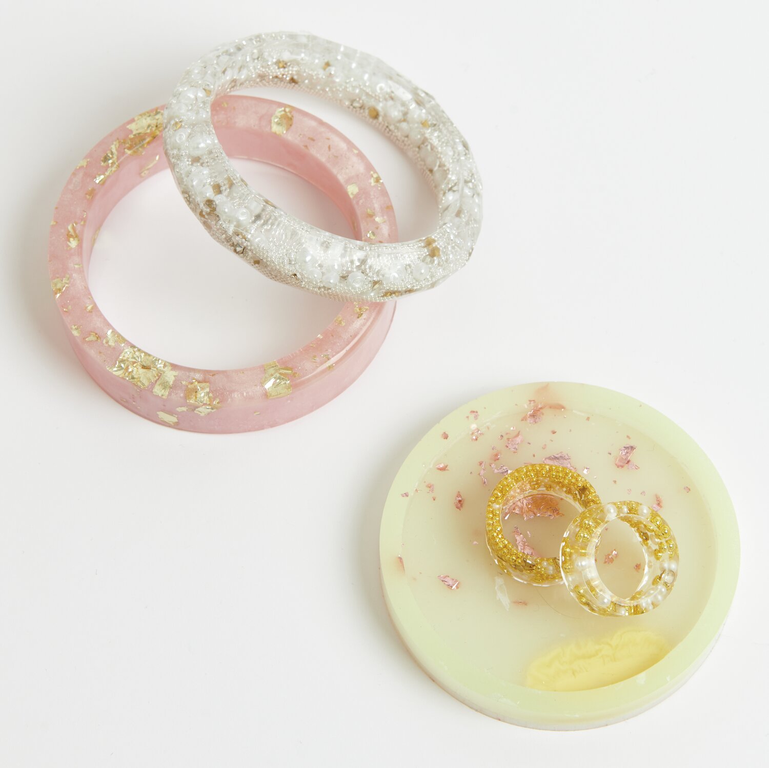 UV Resin Soft: Zwei Armreifen und ein Untersetzer aus transparentem Epoxidharz mit goldenen Akzenten von Rico Design.