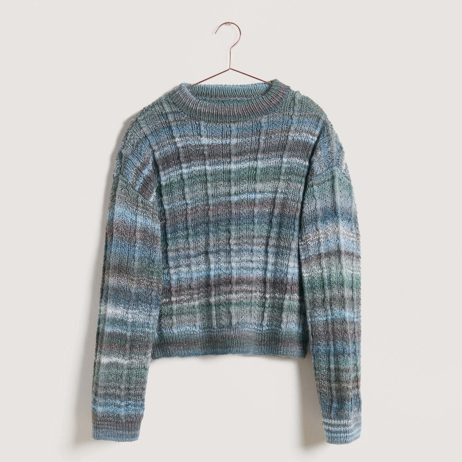 Blauer Pullover auf grauem Hintergrund – zum Strickset