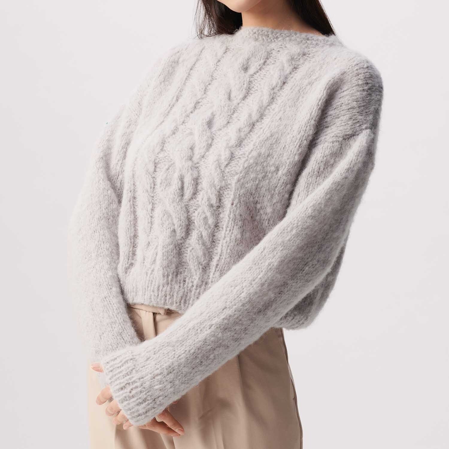 Strickanleitung Pullover aus Fashion Light Luxury: Weicher, grauer Pullover mit Zopfmuster, kombiniert mit beiger Hose. Ideal für kühle Tage.