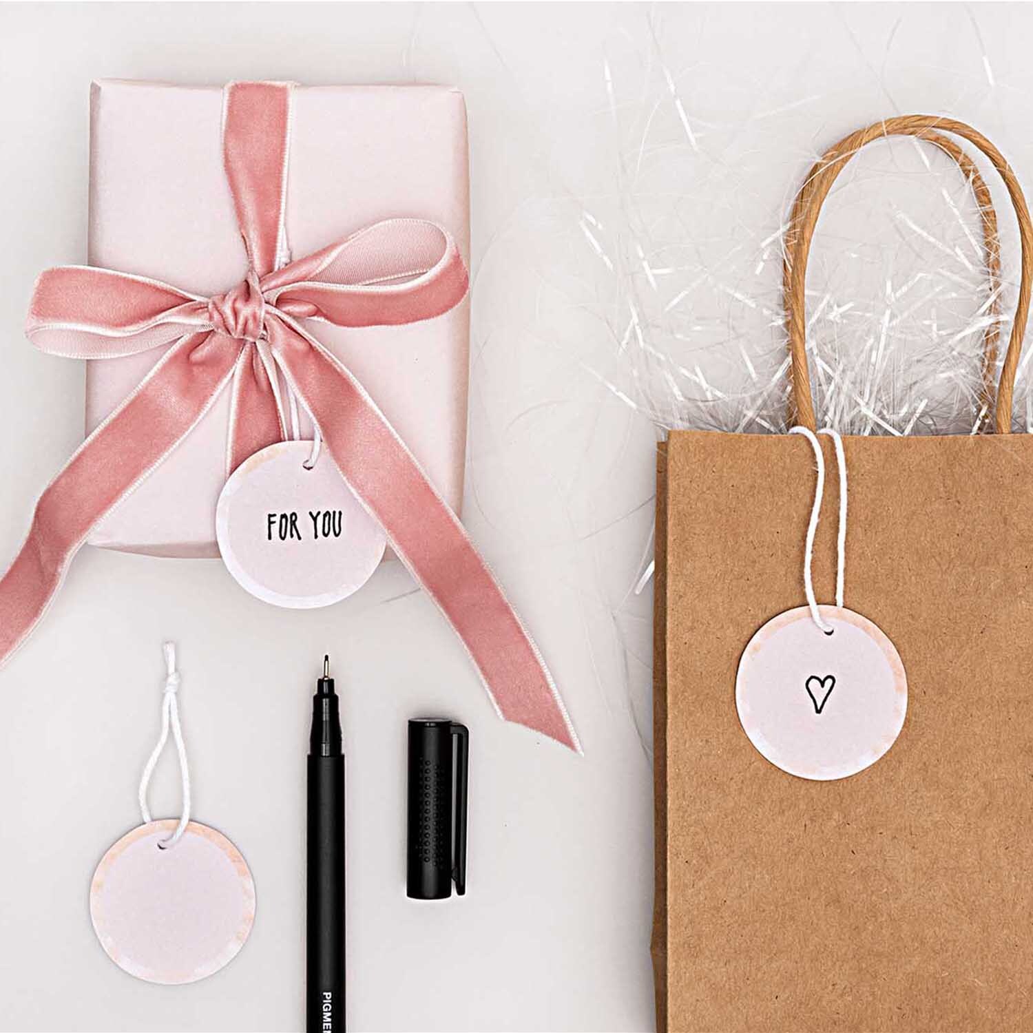 Paper Poetry Papieranhänger Kreise 4cm 24 Stück in Puder, dekoriert mit Geschenk und Tüte. Ideal für kreative Verpackungen.