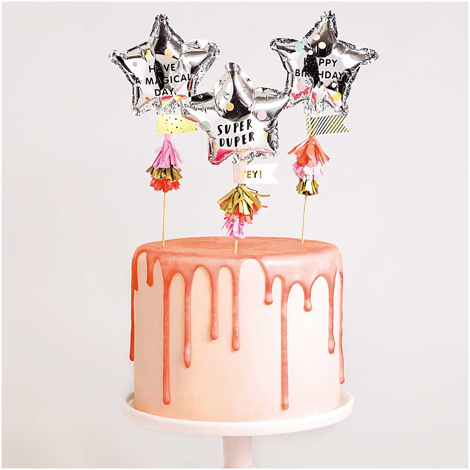 Kuchentopper Folienballon-Sterne von Rico Design: Drei silberne Sternballons auf einer rosa Drip-Torte.