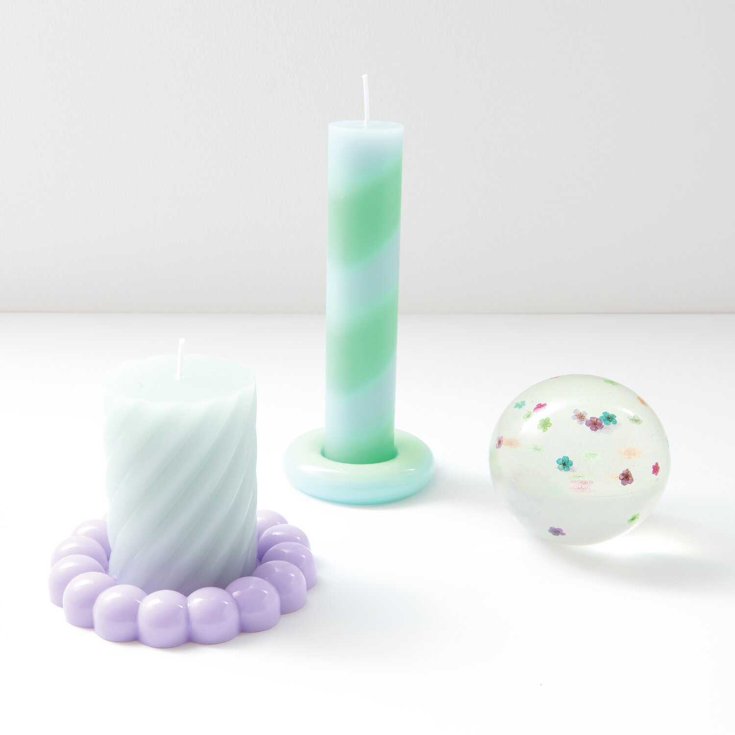 Füllmaterial für Resin Trockenblumen Bunt von Rico Design, dekoriert mit Kerzen und einer Glaskugel.