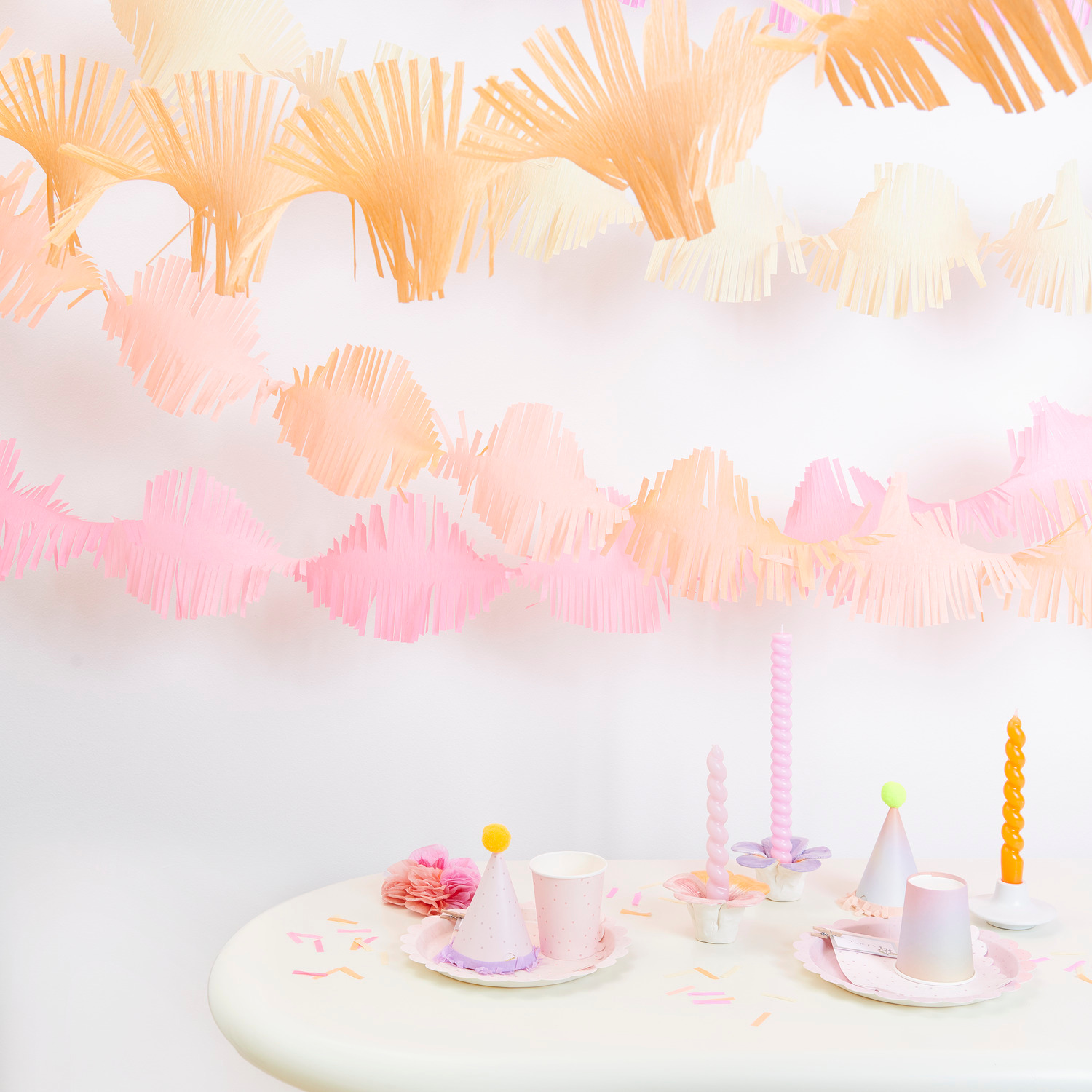 Krepp-Girlande gedreht Blüten Mix: Bunte Papiergirlanden in Pastelltönen dekorieren einen Tisch mit Partyzubehör.