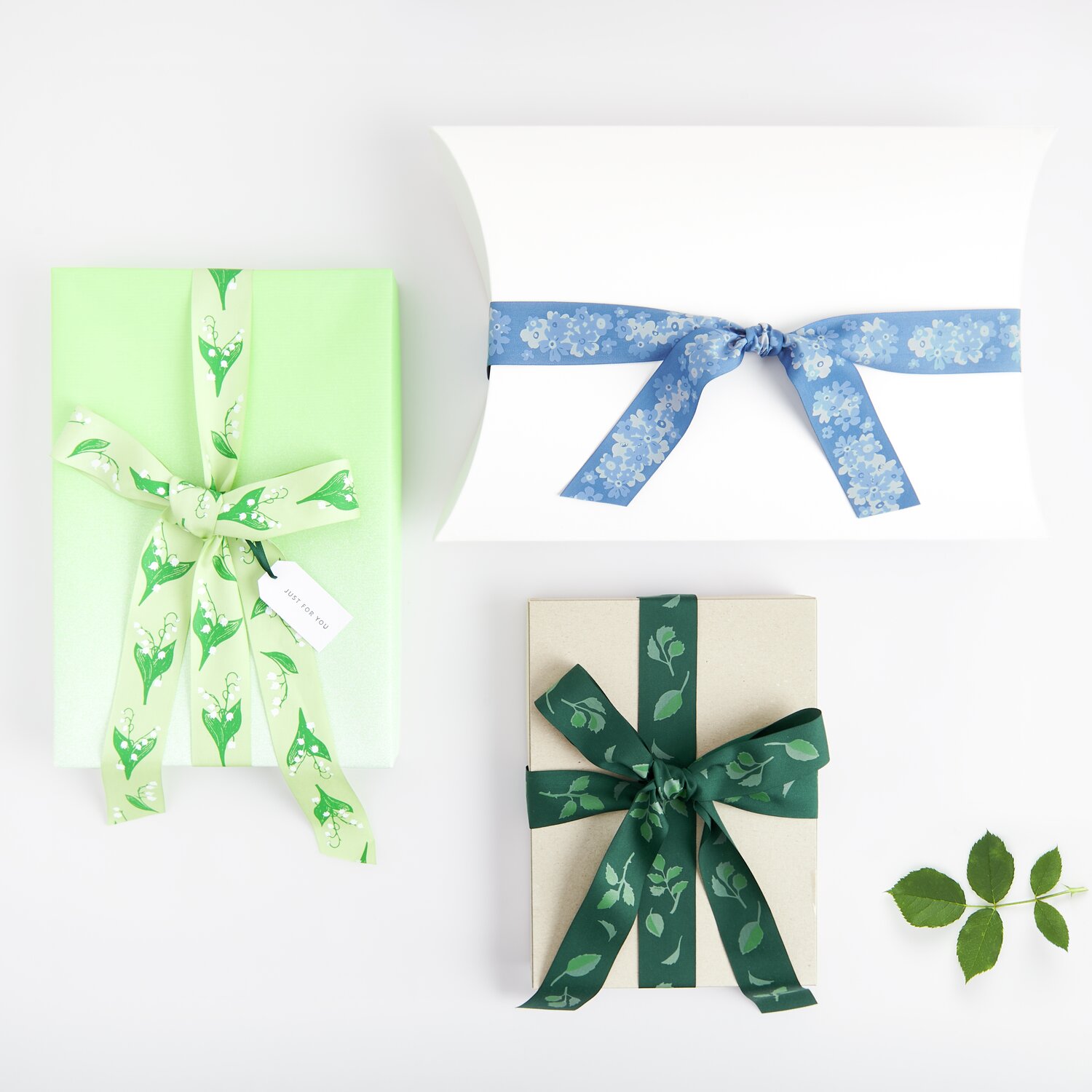 Paper Poetry Taftband Schneeglöckchen: Drei Geschenke mit grünem, blauem und blättrigem Taftband von Rico Design.