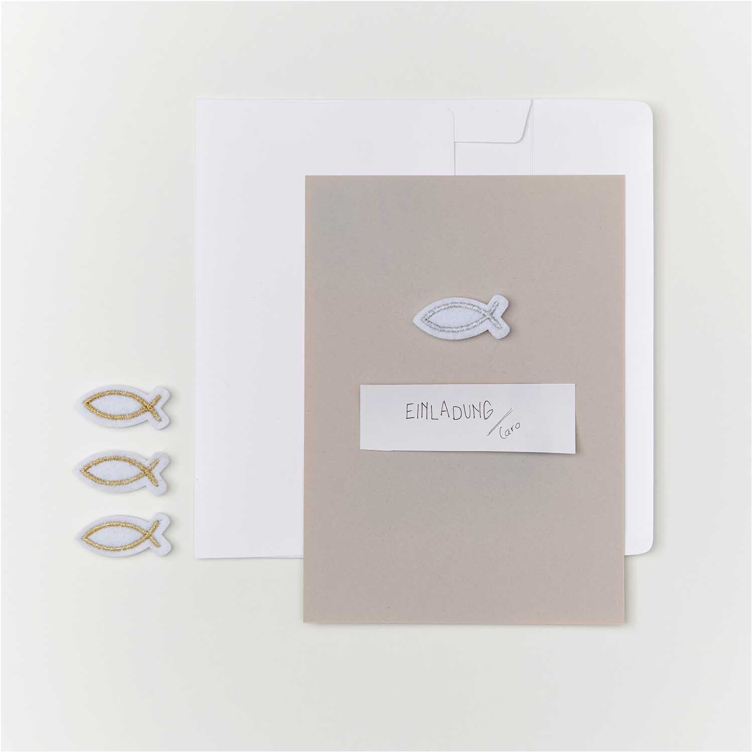 Filzstreu Fisch weiß-silber 12 Stück: Dekorative Fische aus Filz auf grauer Karte mit Umschlag. Ideal für Einladungen.