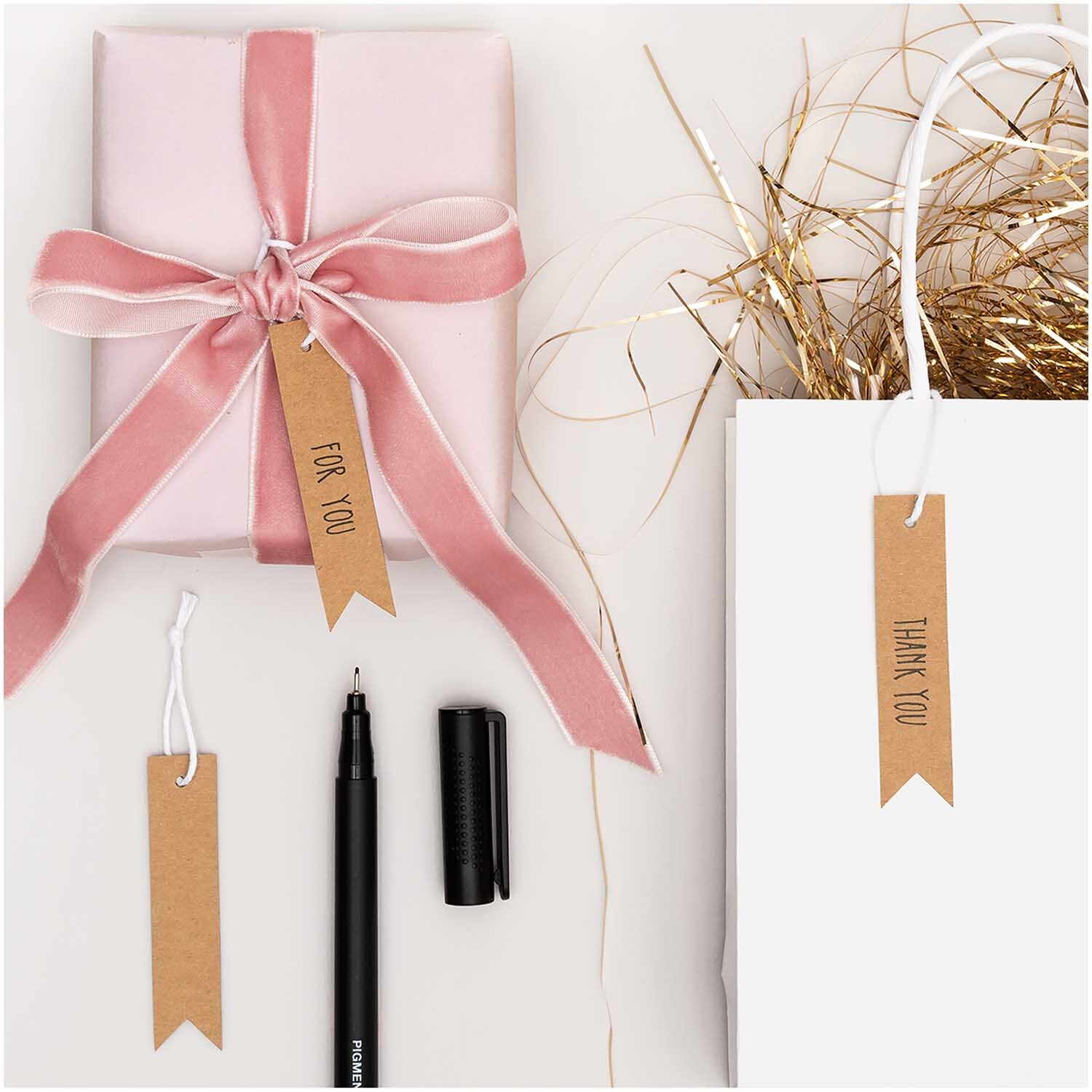 Paper Poetry Papieranhänger aus Kraftpapier in Braun, dekorativ an Geschenk und Tüte befestigt.