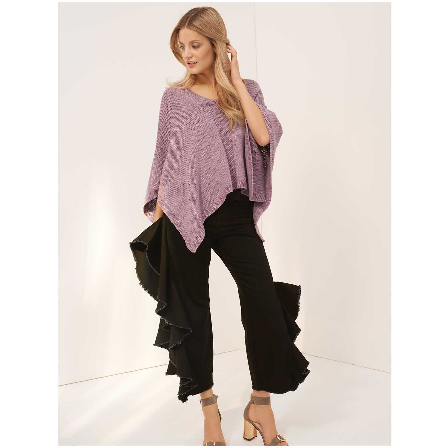 Fashion Balance dk: Frau in fliederfarbenem Poncho von Rico Design, kombiniert mit schwarzen Rüschenhosen.