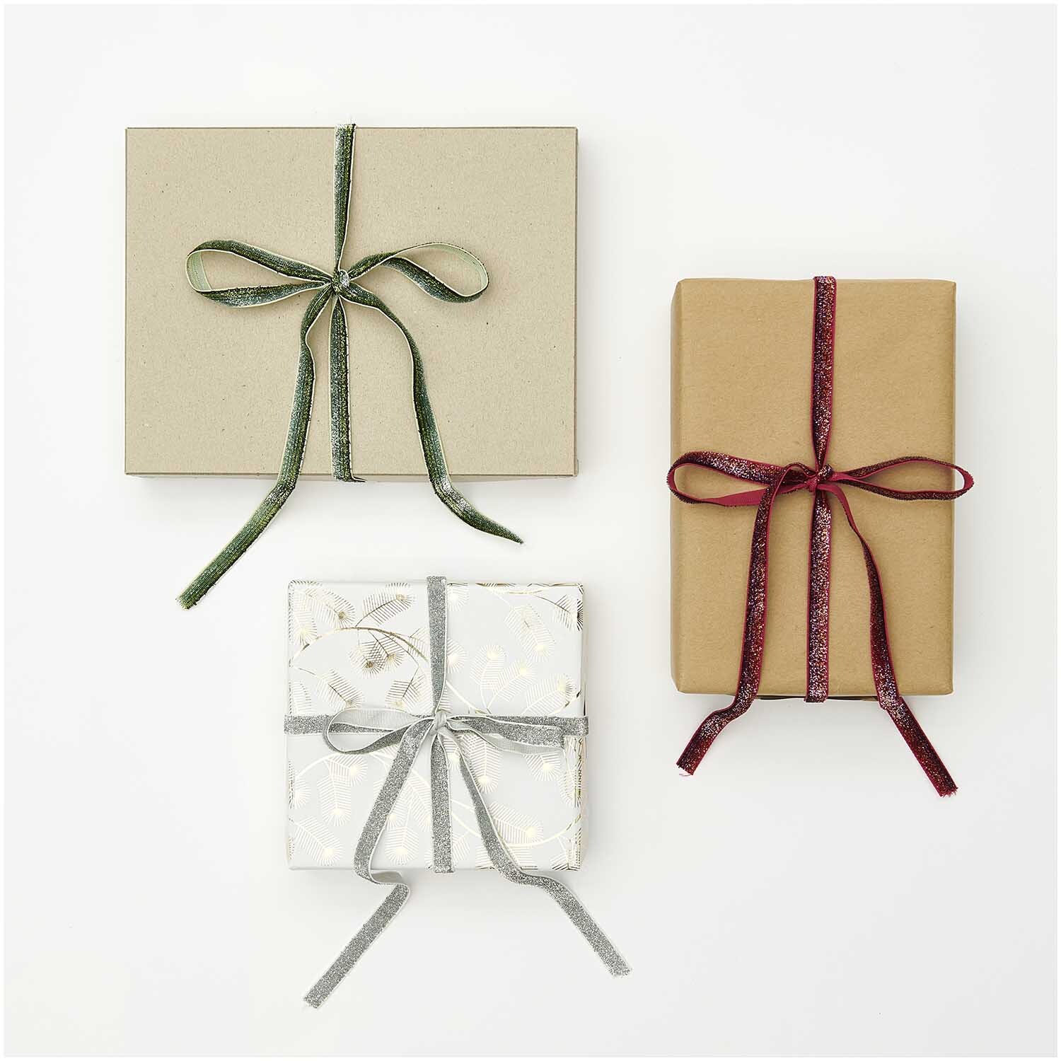 Paper Poetry Glitzerband 10mm 3m von Rico Design, irisierend, verziert drei elegant verpackte Geschenke.