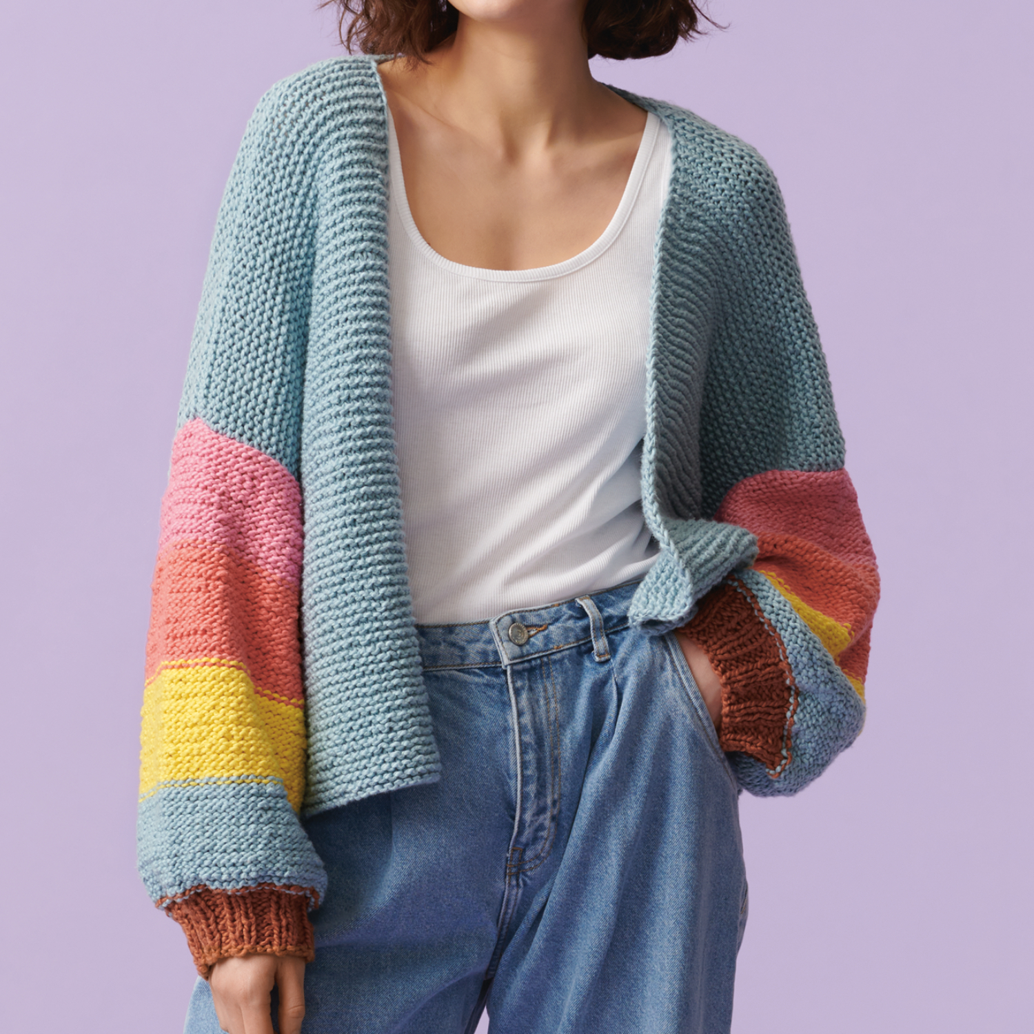Strickanleitung Jacke aus Creative So Cool & So Soft Print: Bunte Strickjacke mit Farbverlauf in Blau, Rosa, Gelb und Braun vor lila Hintergrund.