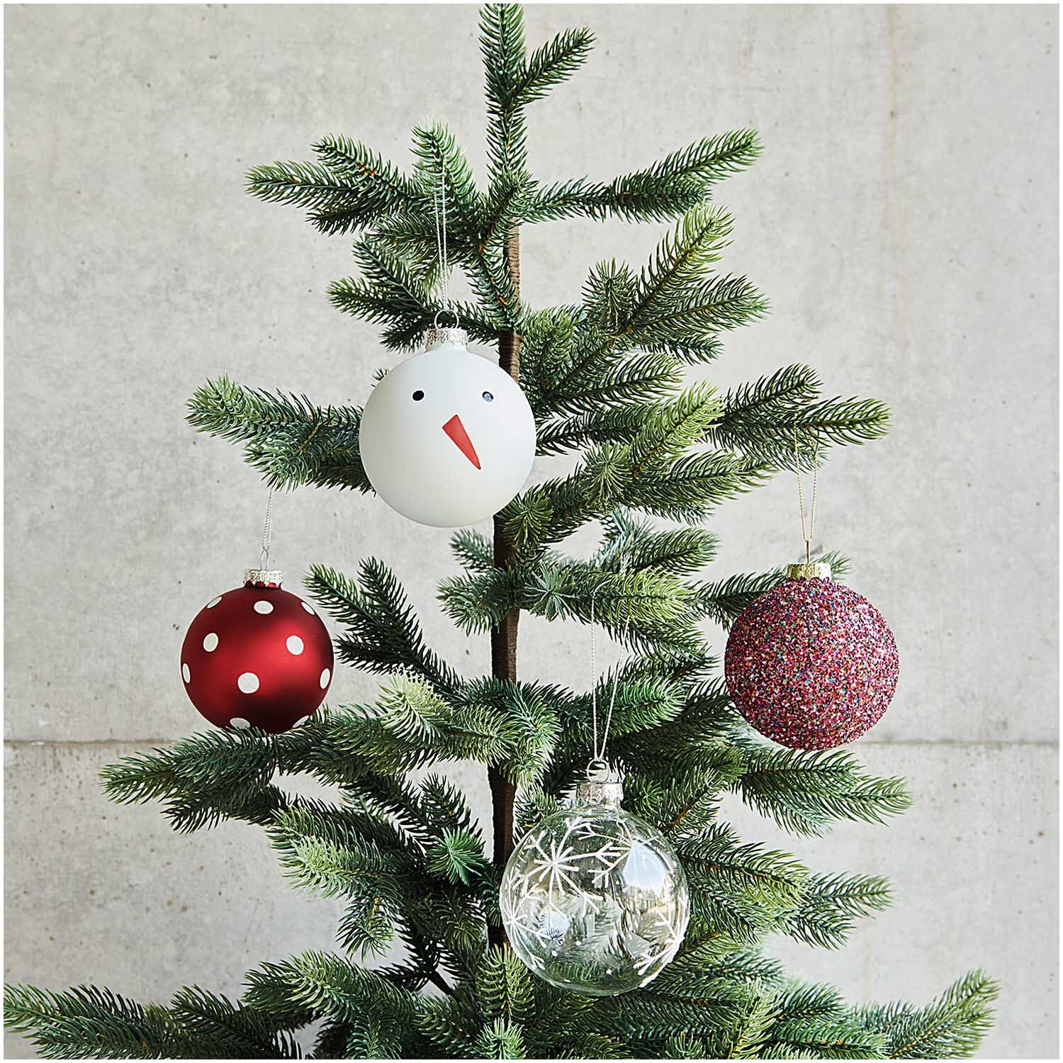 Glaskugel Baumschmuck Schneemann 8cm von Rico Design: Weißer Schneemann-Anhänger an einem Tannenbaum, umgeben von weiteren dekorativen Kugeln.