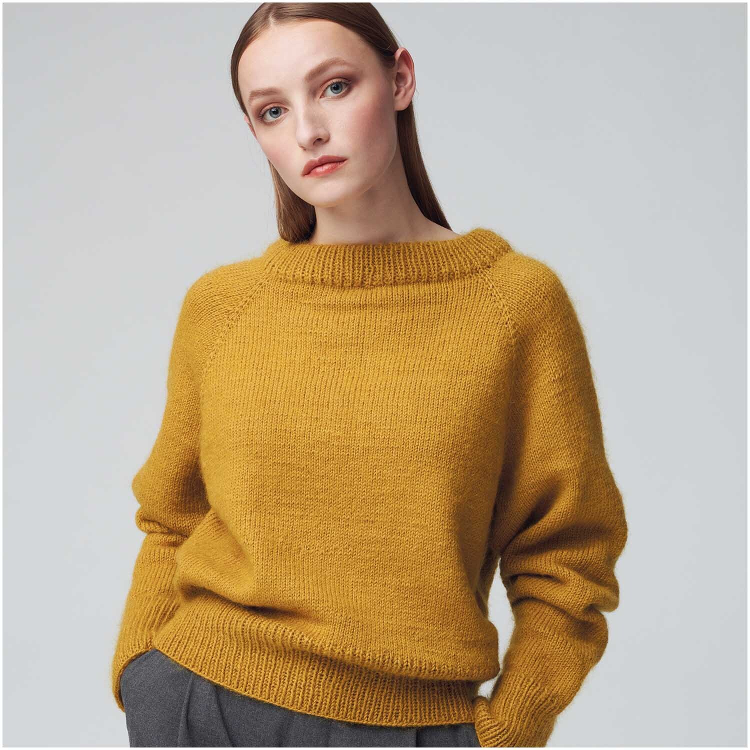Essentials Merino dk Pullover in Senf, gestrickt aus weicher Wolle von Rico Design, getragen von einer Frau.
