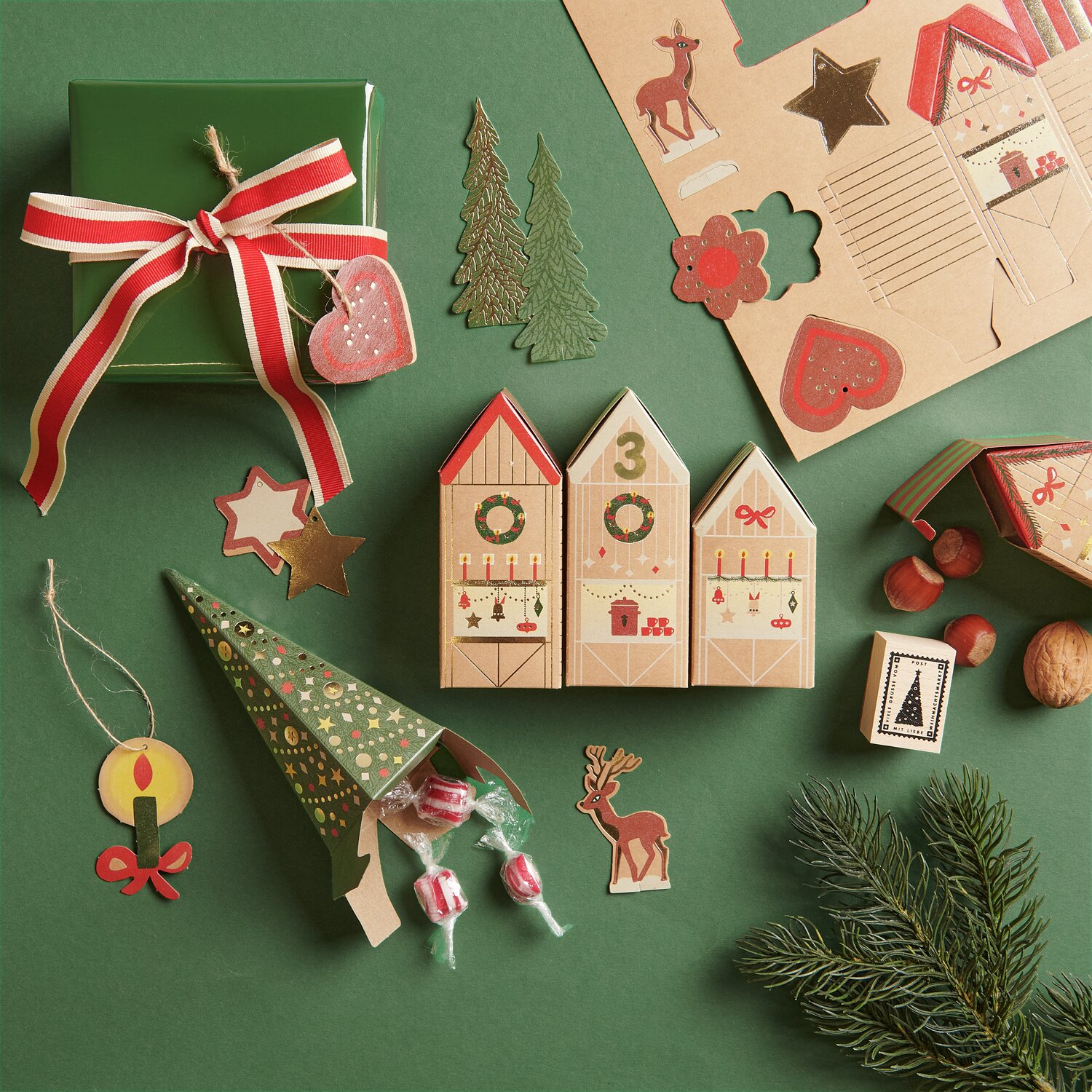 Adventskalender Bastelset mit weihnachtlichen Motiven, grüner Hintergrund, rote Akzente.