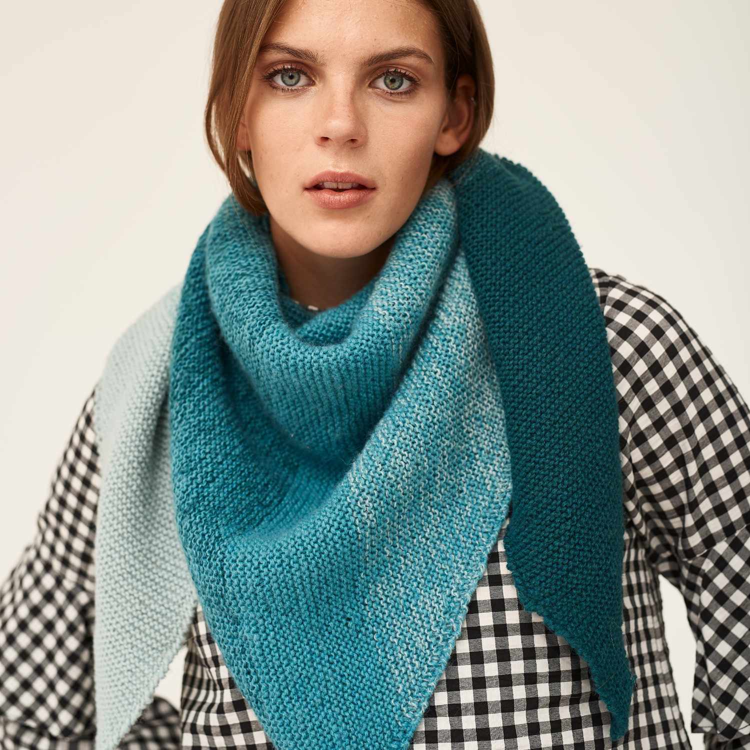 Creative Wool dégradé: Frau trägt ein gestricktes, blaues Dreieckstuch von Rico Design über kariertem Hemd.