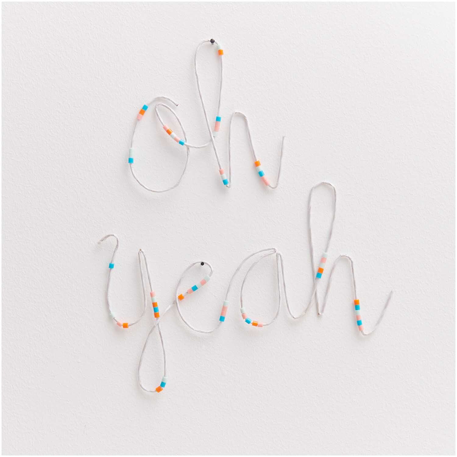 Papierdraht 1,8mm 1m 10 Stück formt die Worte "oh yeah" mit bunten Perlen auf weißem Hintergrund.