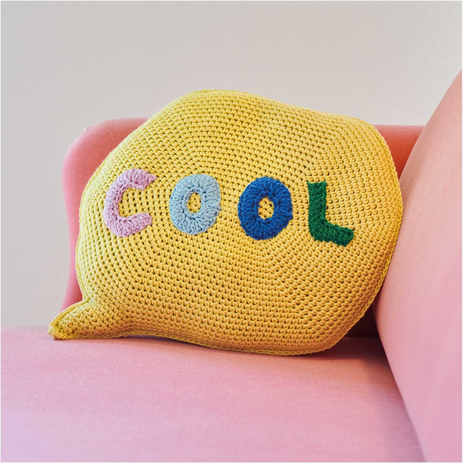 Creative Cotton aran Kissen in Hellgelb mit buntem "Cool"-Schriftzug auf rosa Sofa, 50g 85m.