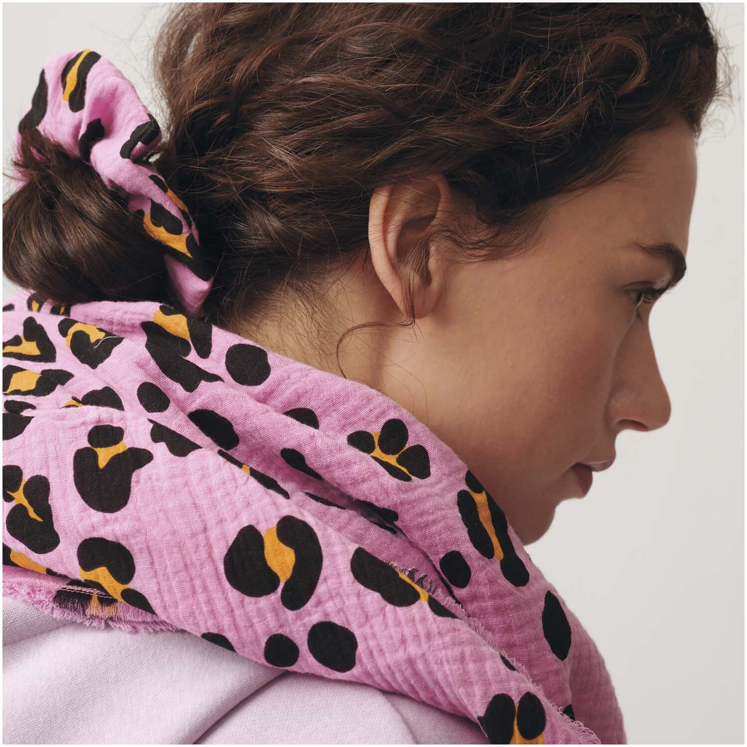 Meterware Krinkelmusselin Acid Leo pink von Rico Design: Frau mit pinkem Tuch mit Leopardenmuster um den Hals.