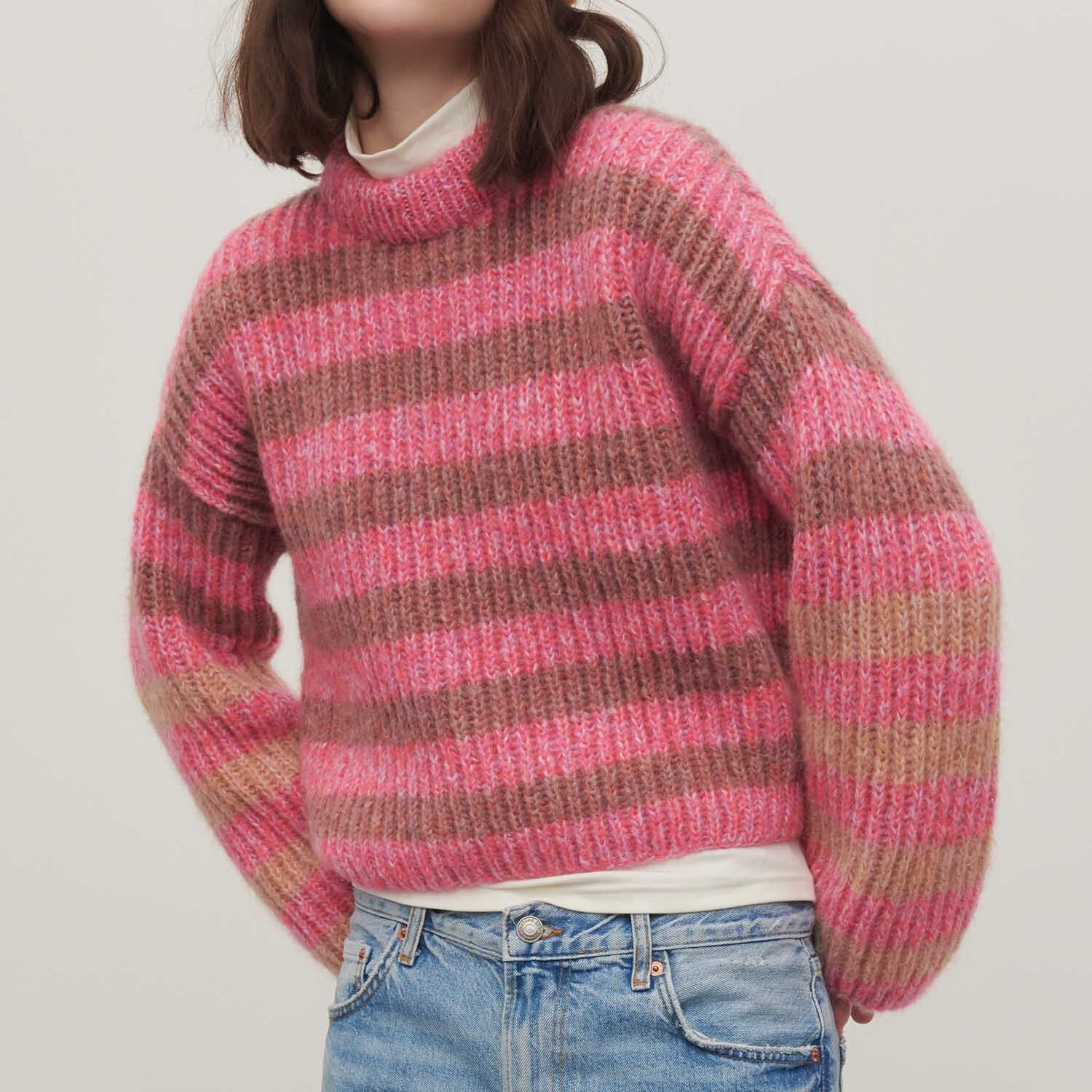 Strickanleitung Pullover aus Fashion Fabulous 4 aran: Gestreifter Pullover in Rosa- und Brauntönen, getragen von einer Person mit blauer Jeans.