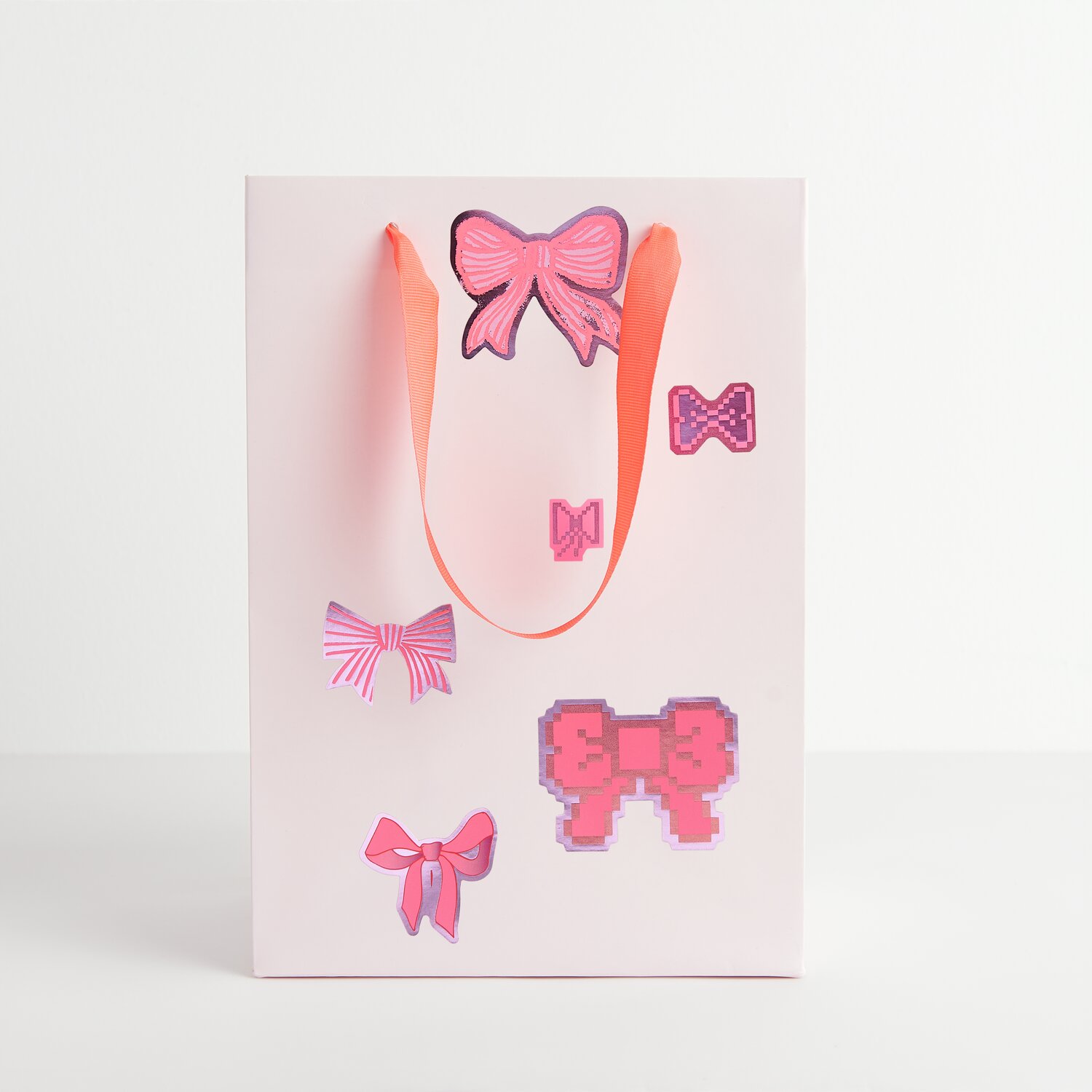 Paper Poetry Sticker Schleifen auf weißer Geschenktüte mit rosa Schleifenmotiven und Griffen.
