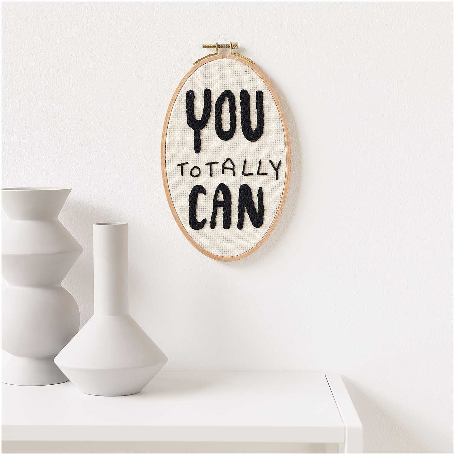 Punch Needle Packung Bild zeigt ein ovales Stickrahmen-Design mit motivierendem Text an einer weißen Wand.