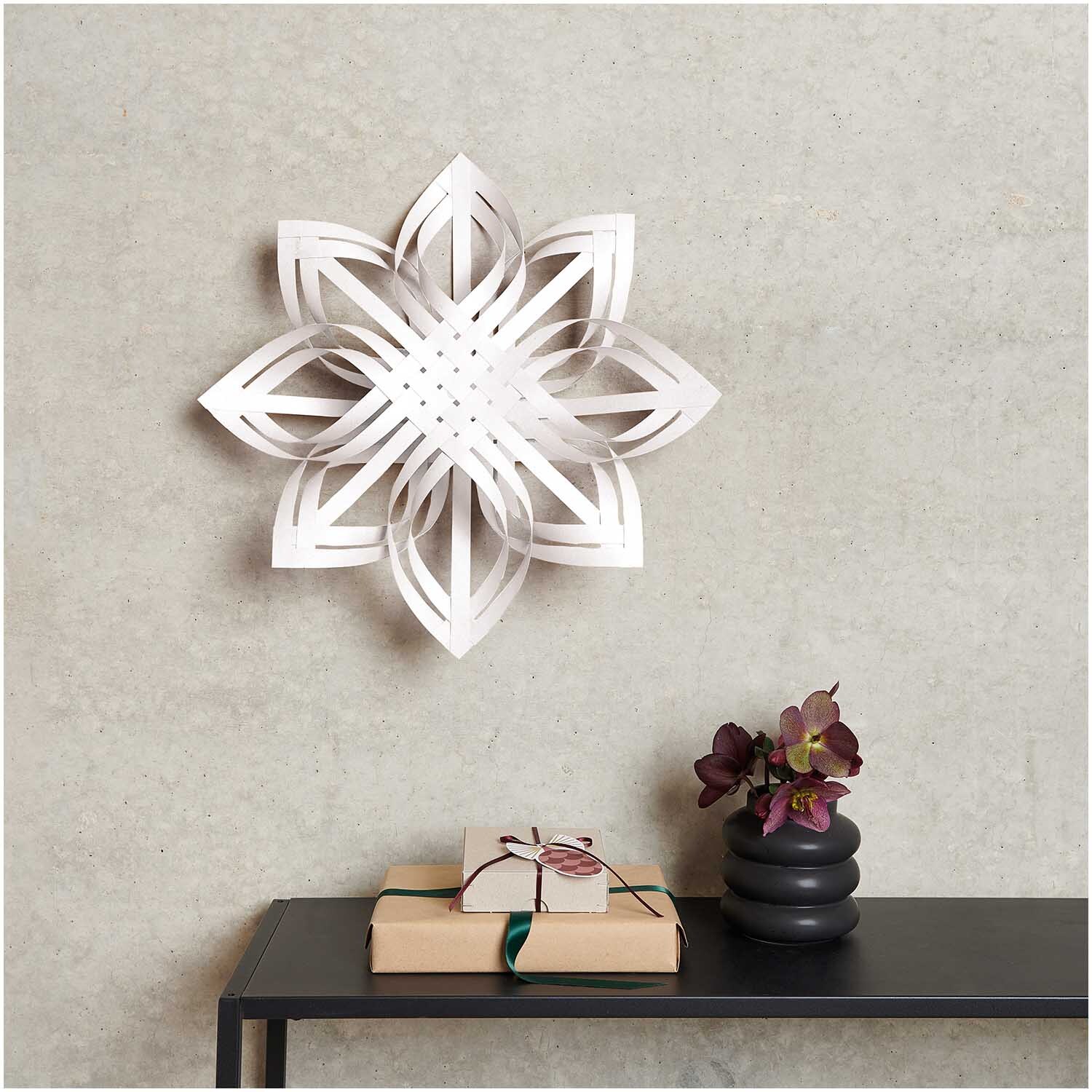 Paper Poetry Web-Stern Größe M an der Wand, dekoriert mit Blumen und Geschenken auf einem Tisch.