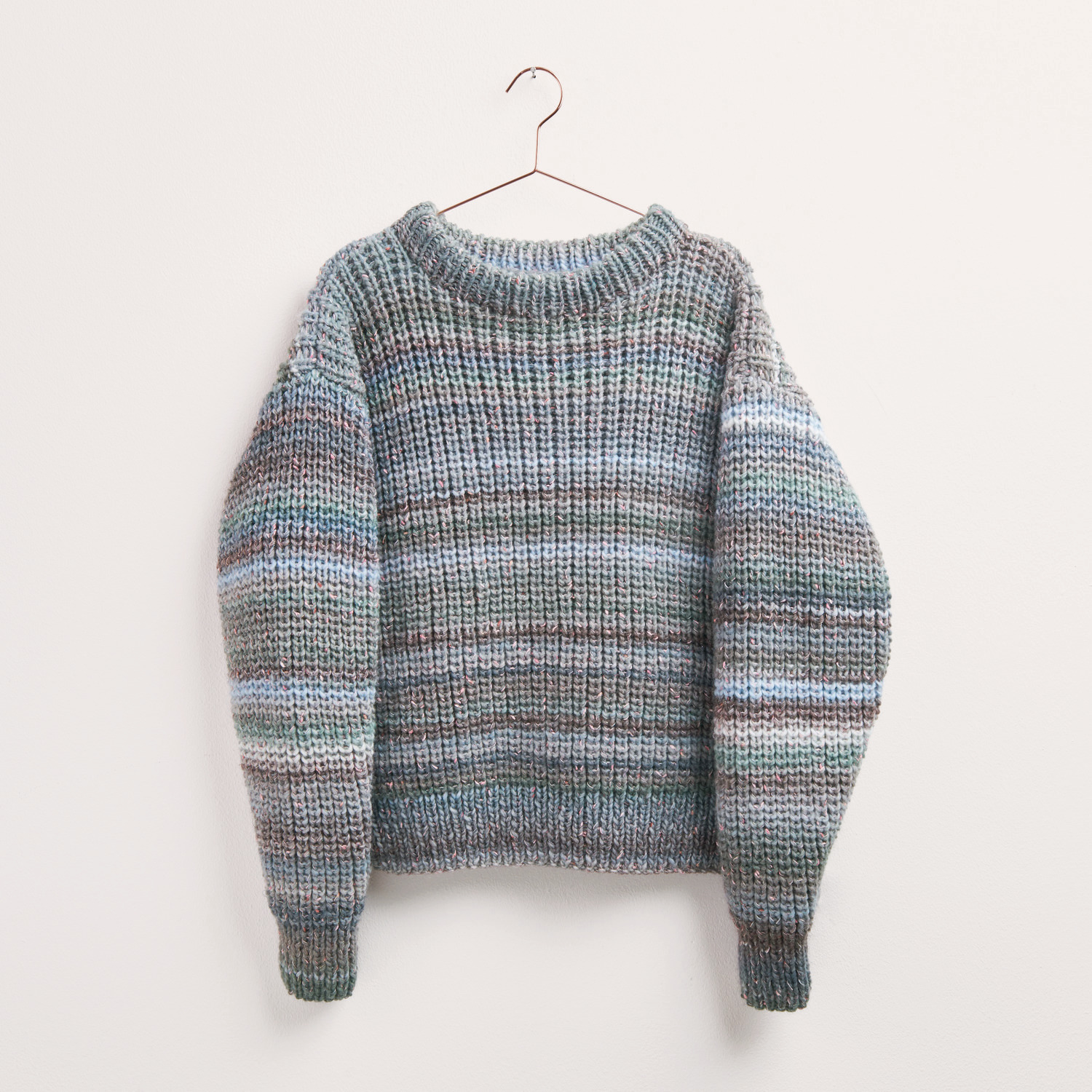 Strickset Pullover Modell 10b: Handgestrickter Pullover in Blau von Rico Design, hängend an einem Kleiderbügel.