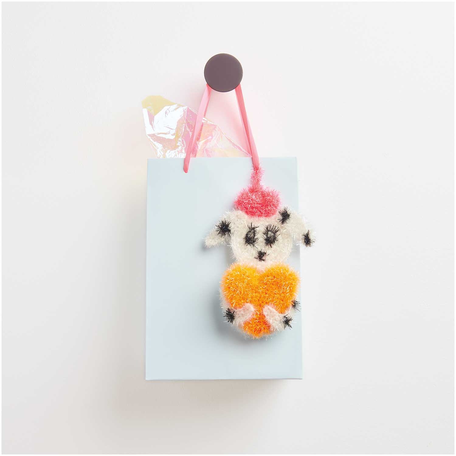 Creative Bubble: Ein gehäkelter Schwamm in Tierform hängt an einer hellblauen Geschenktüte.