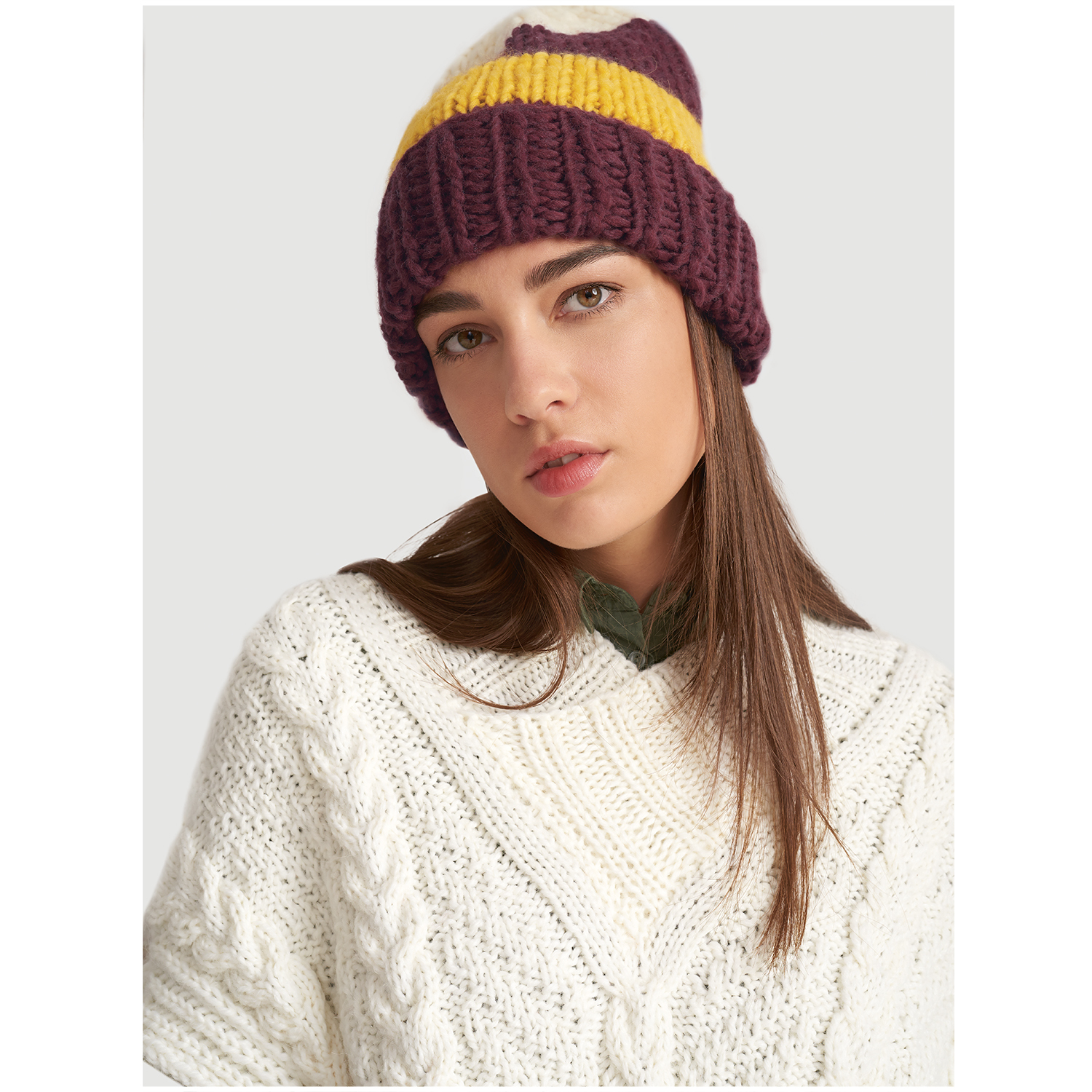 Essentials Super super chunky: Frau trägt gestrickte Mütze in Gelb und Lila von Rico Design, passend zu weißem Pullover.