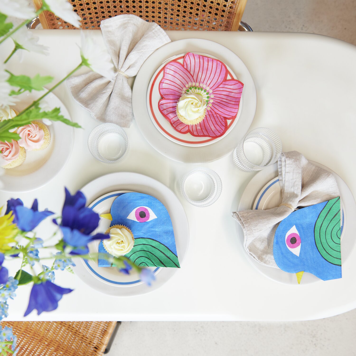 Servietten Schwalbe: Bunte Tischdekoration mit farbenfrohen Servietten von Rico Design auf weißem Tisch.