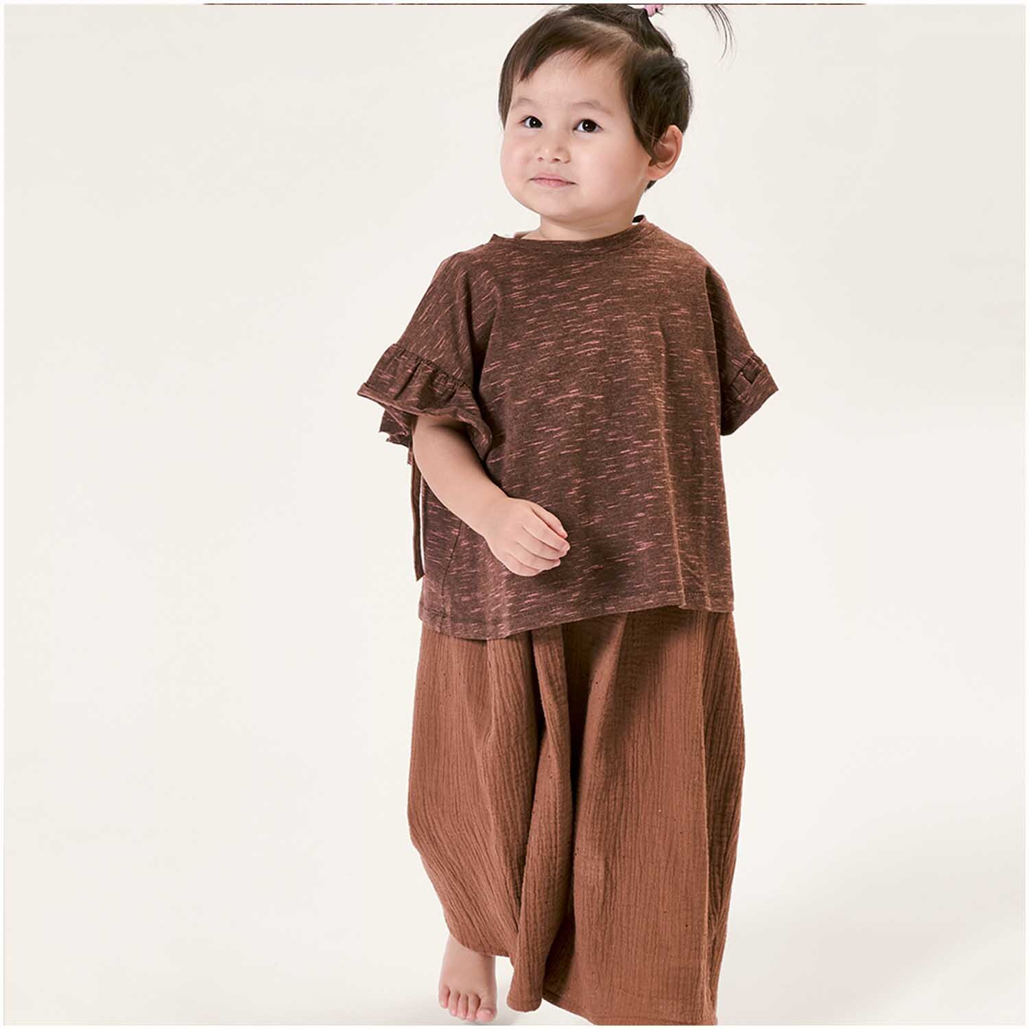 Meterware Krinkelmusselin kastanie Hot Foil: Kind in kastanienbraunem Outfit aus weichem Musselin-Stoff von Rico Design.