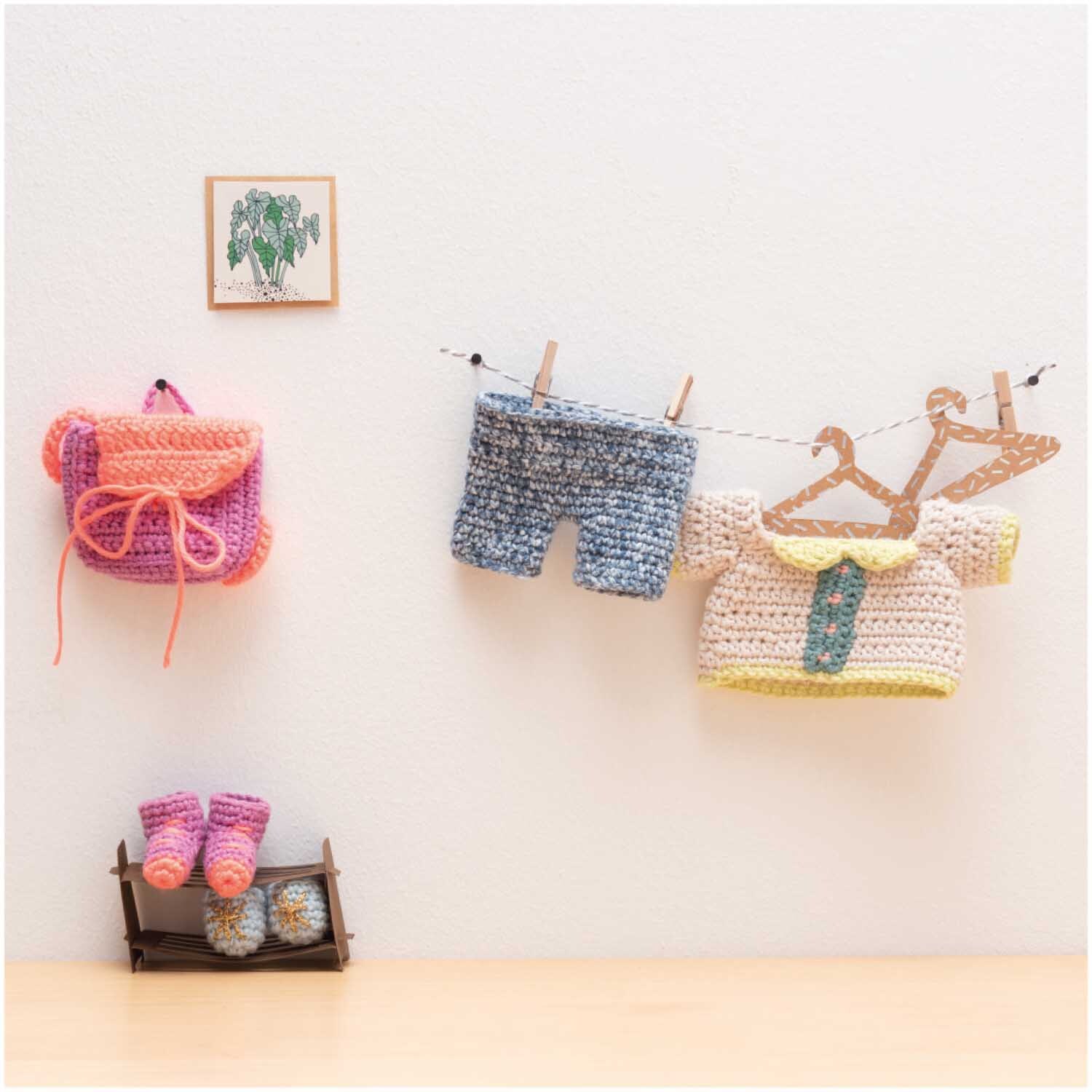 Creative Ricorumi Neon dk: Gehäkelte Babybekleidung und Accessoires in Neon-Orange, an einer Leine hängend.