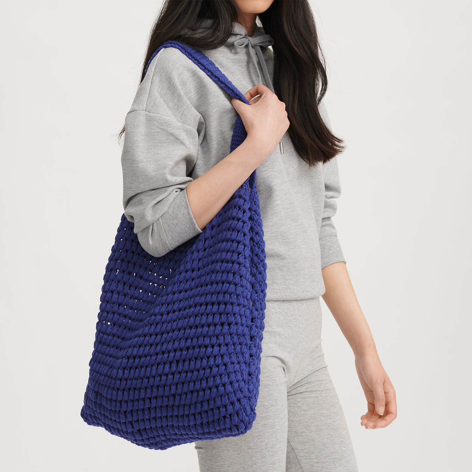 Häkelanleitung Tasche aus Creative Cotton aran: Frau trägt eine große, blaue gehäkelte Tasche.
