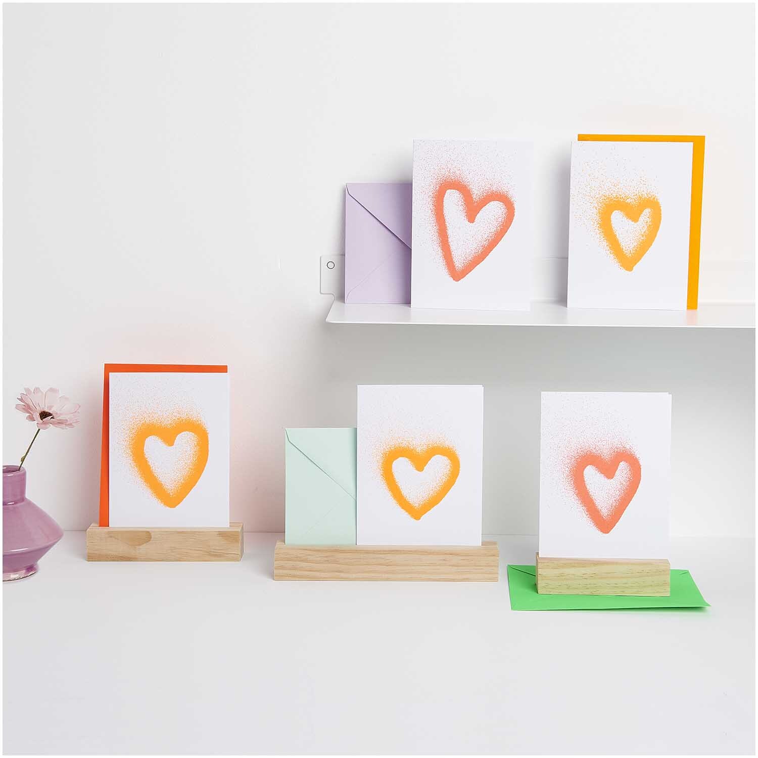 Paper Poetry Kartenset Airbrush Herzen B6 zeigt Karten mit orangefarbenen Herzen auf Holzständern.