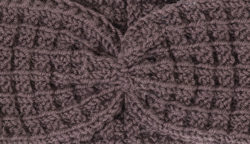 Strickanleitung Stirnband aus Siena: Nahaufnahme eines gestrickten, braunen Stirnbands mit detailliertem Muster.