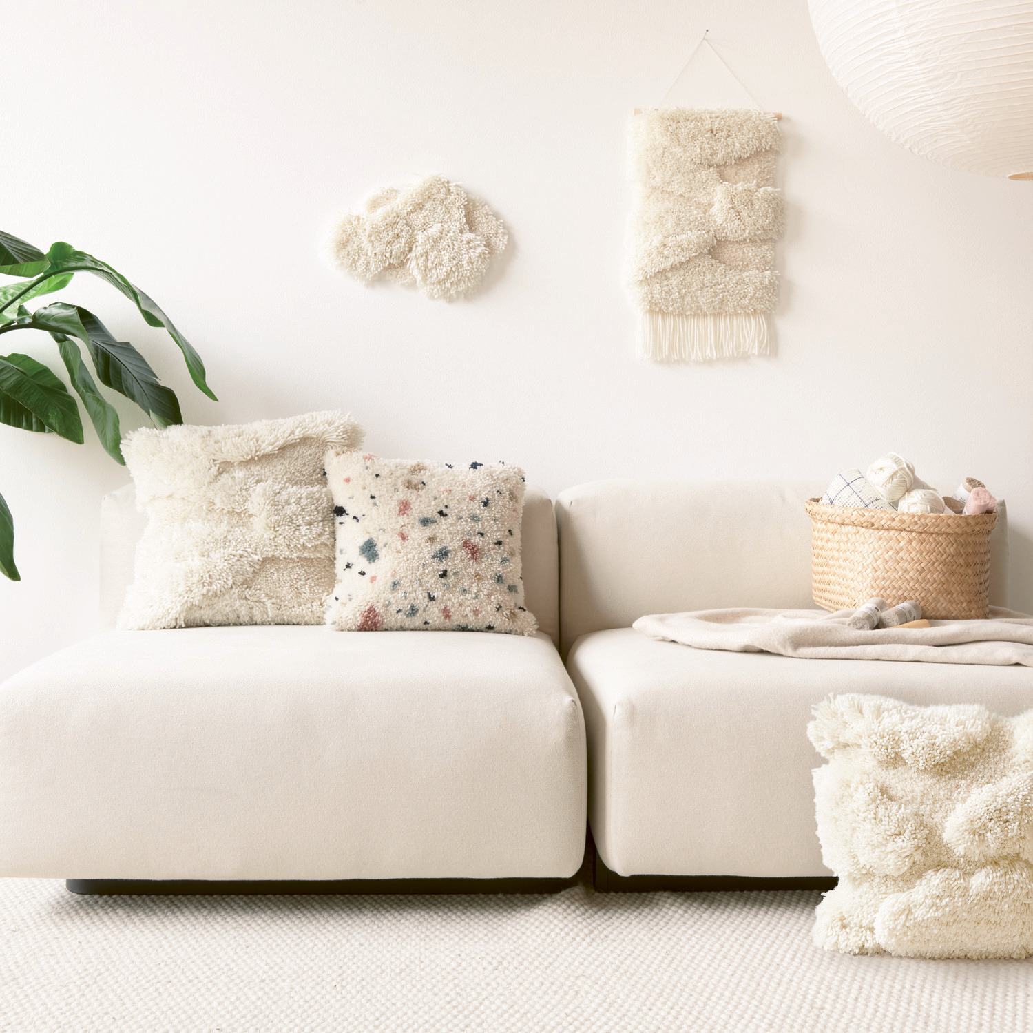 Rico Hooki Hooki Knüpfgarn in Offwhite und Altrosa dekoriert ein modernes Wohnzimmer mit Kissen und Wandbehängen. Ideal für stilvolle Akzente.