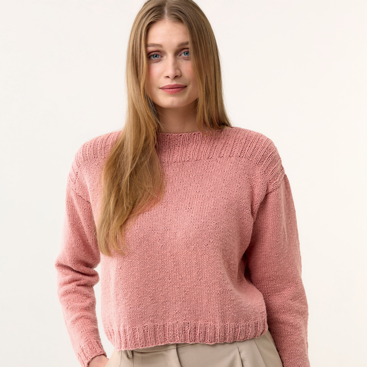 Strickset Pullover Modell 03: Frau trägt einen rosa Pullover mit langen Ärmeln, schlichtes Design.