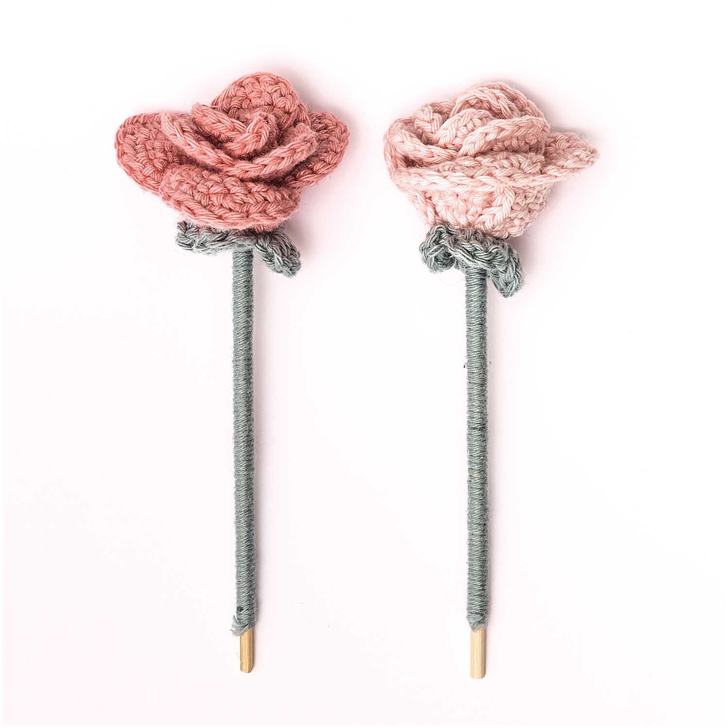 Creative Ricorumi dk: Zwei gehäkelte Rosen in Rosa von Rico Design, jeweils auf einem Stiel befestigt.