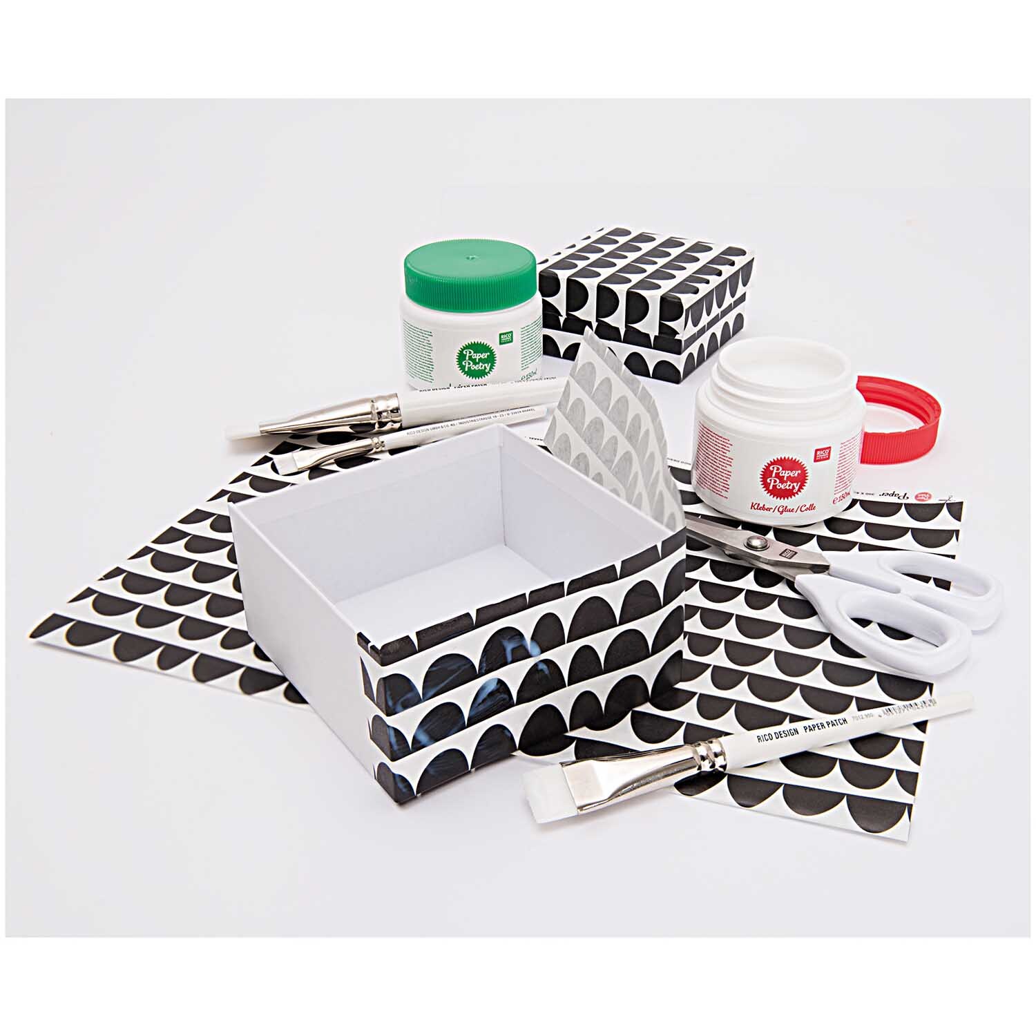 Lack 150ml: Bastelset mit schwarz-weiß gemusterten Boxen, Pinseln, Schere und Kleber. Ideal für kreative Projekte.