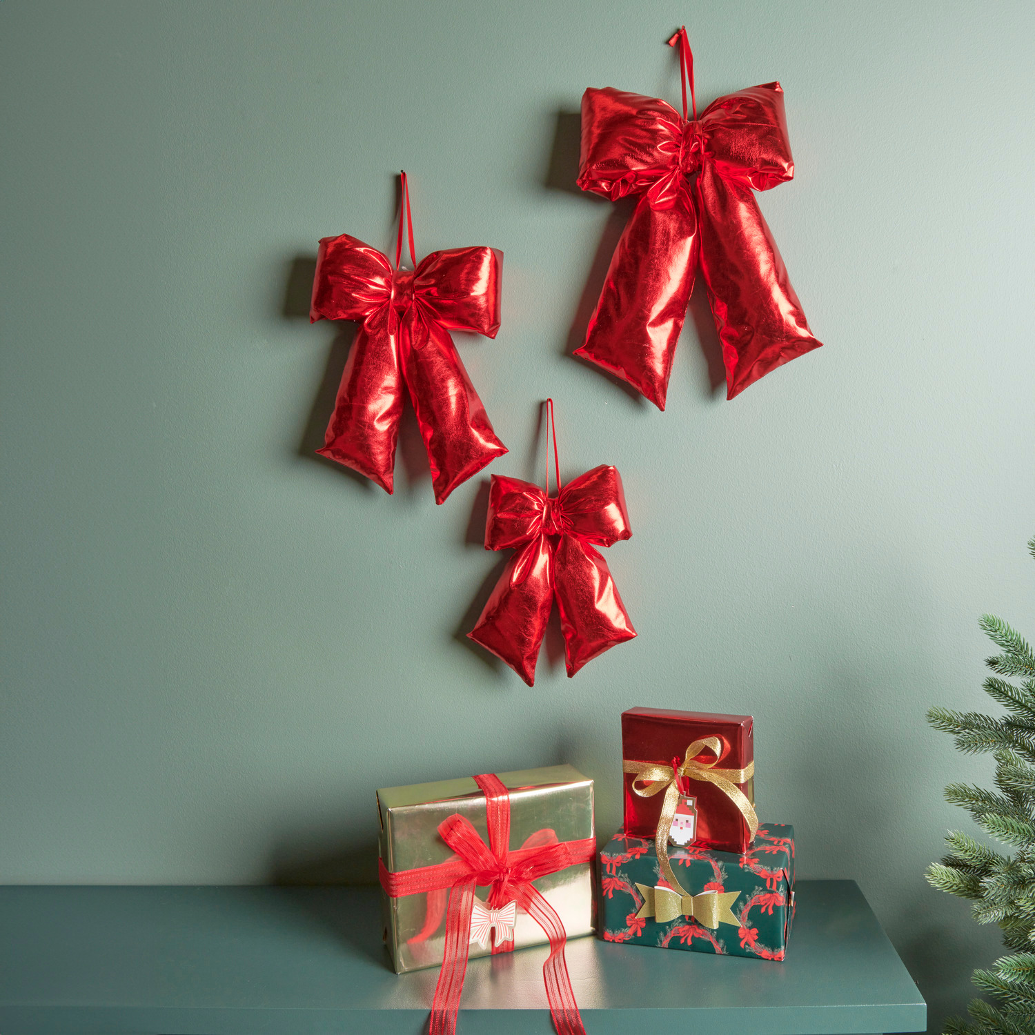 Weihnachtsschleife Rot: Drei glänzende 3D-Sticker-Schleifen von Paper Poetry an grüner Wand.
