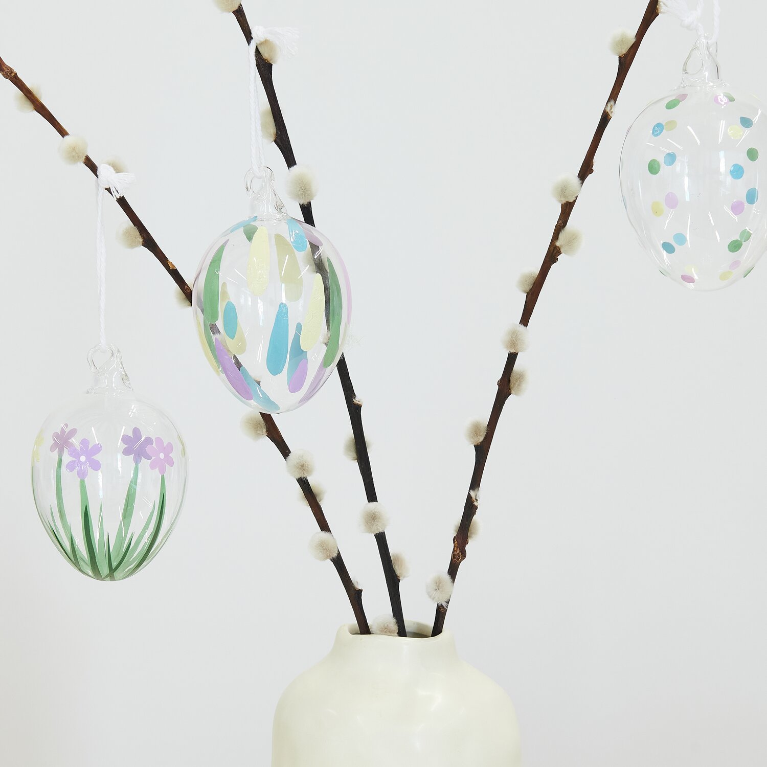 Glas Ei Tropfen: Bunte Glastropfen-Eier von Rico Design an Zweigen in weißer Vase dekoriert.