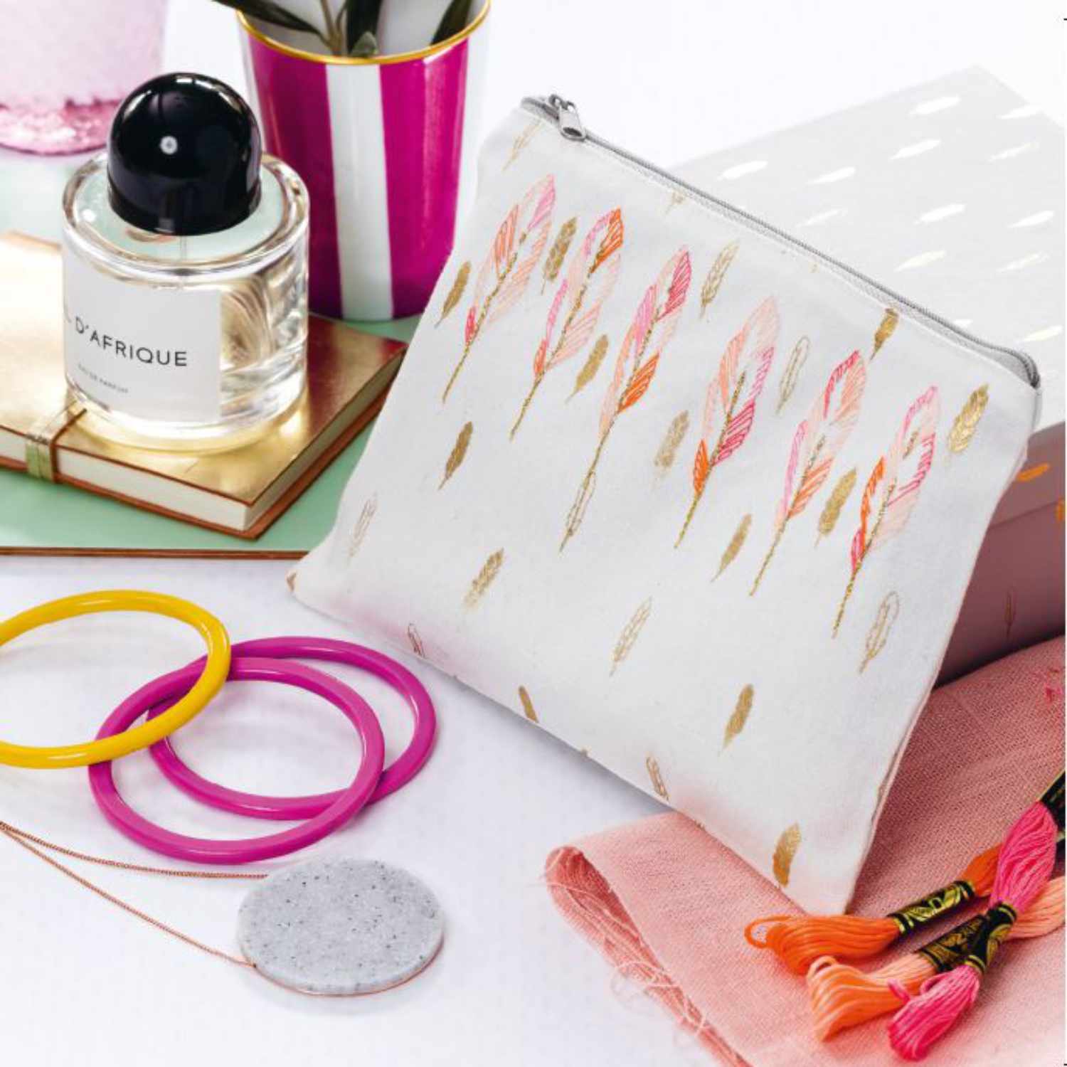 Sticken lernen leicht gemacht: Kosmetiktasche mit floralen Mustern, umgeben von Stickgarn und Accessoires.