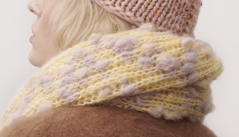 Strickanleitung Schal aus Fashion Alpaca Vibes: Frau mit gelbem, flauschigem Schal und rosa Mütze.